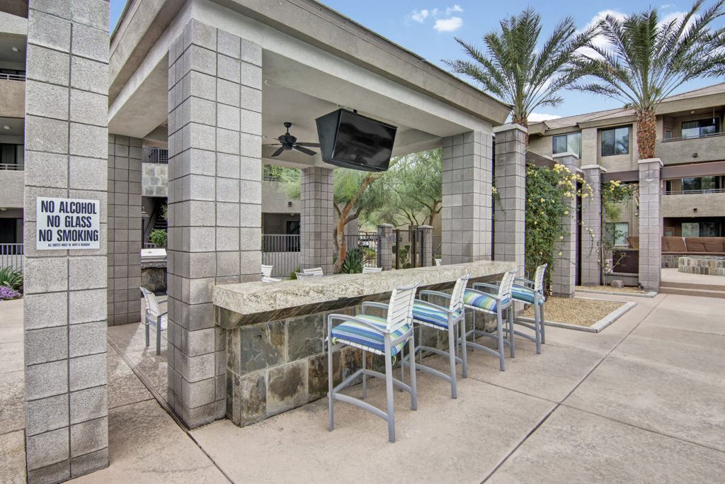 A pavilion with a bar and chairs in front of a building.