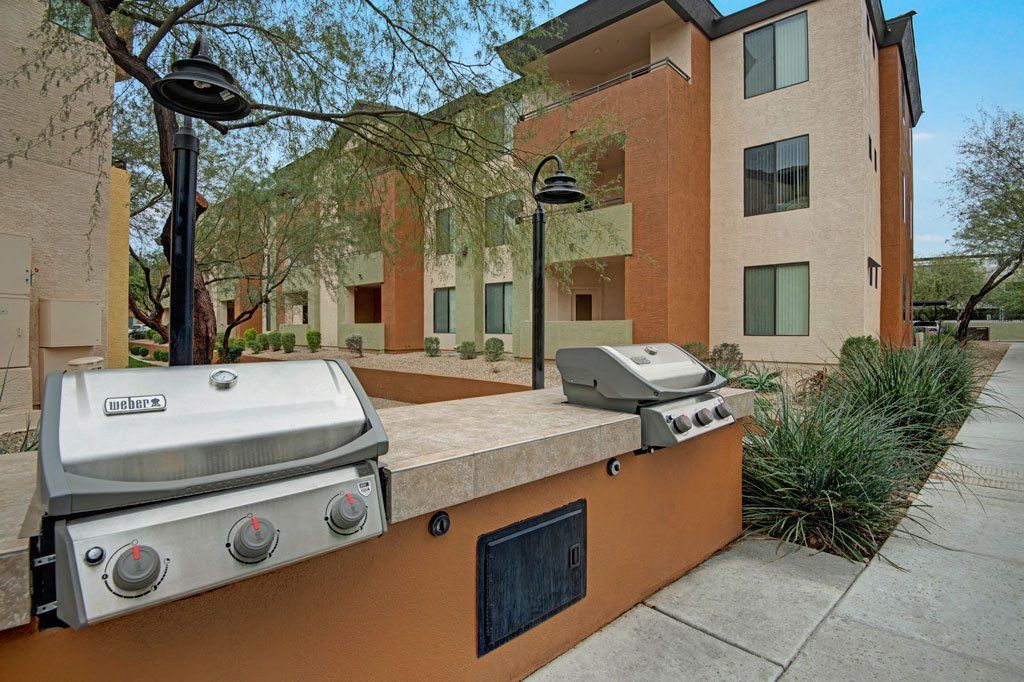 A grill is sitting on a sidewalk in front of a building.