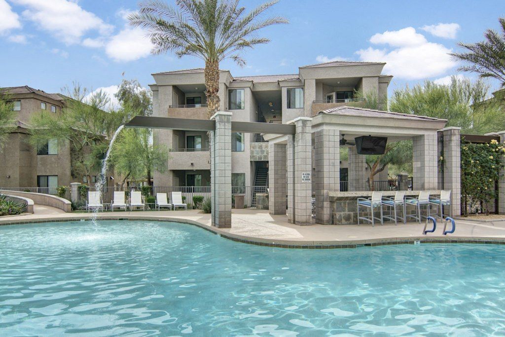 A large swimming pool with a fountain in front of a building.
