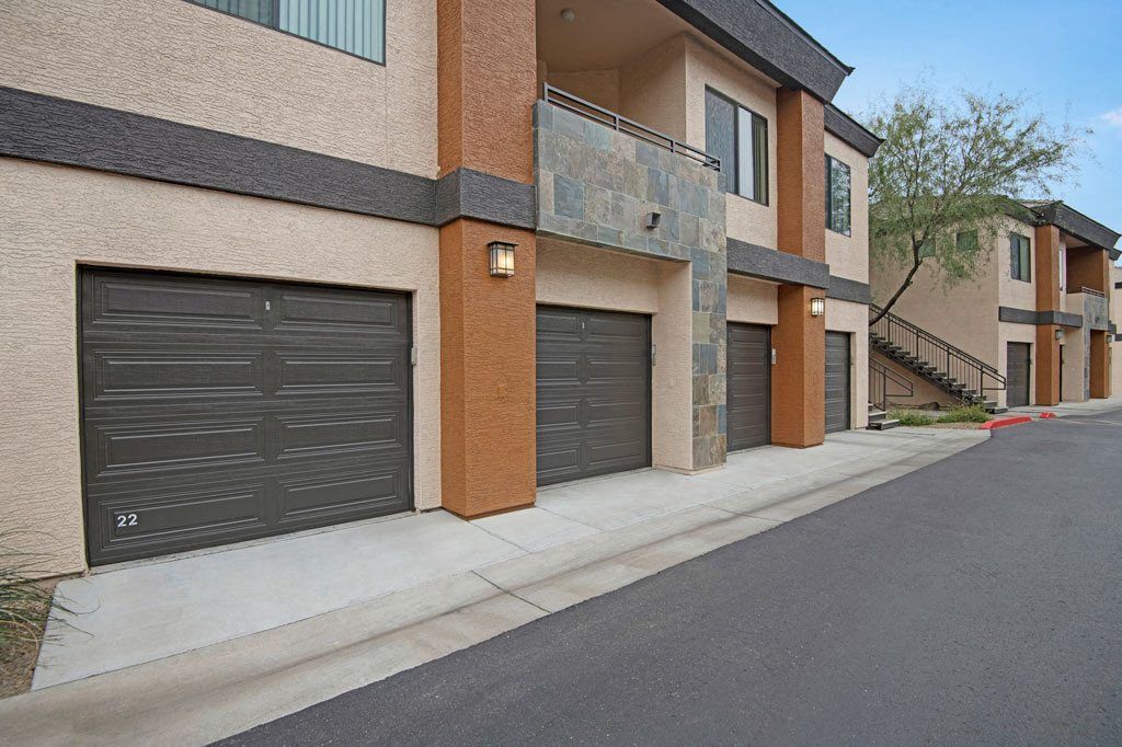 A row of apartment buildings with garages on the side of the road.