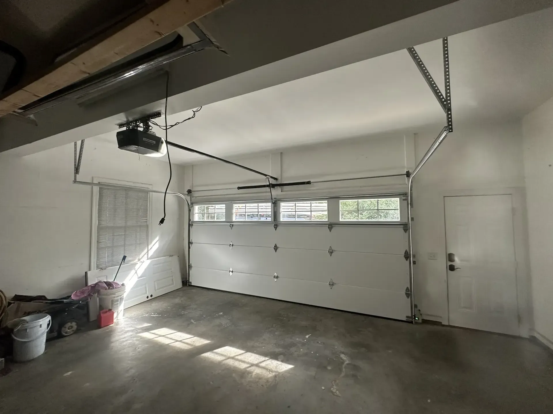 An empty garage with a garage door open and a garage door opener.