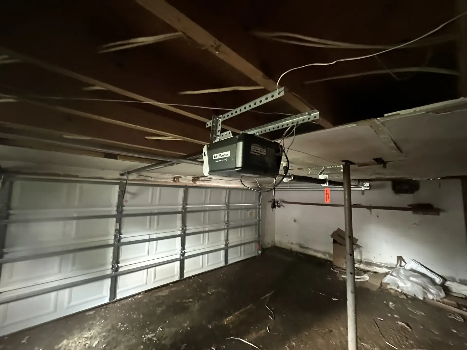 A garage door opener is hanging from the ceiling of a garage.