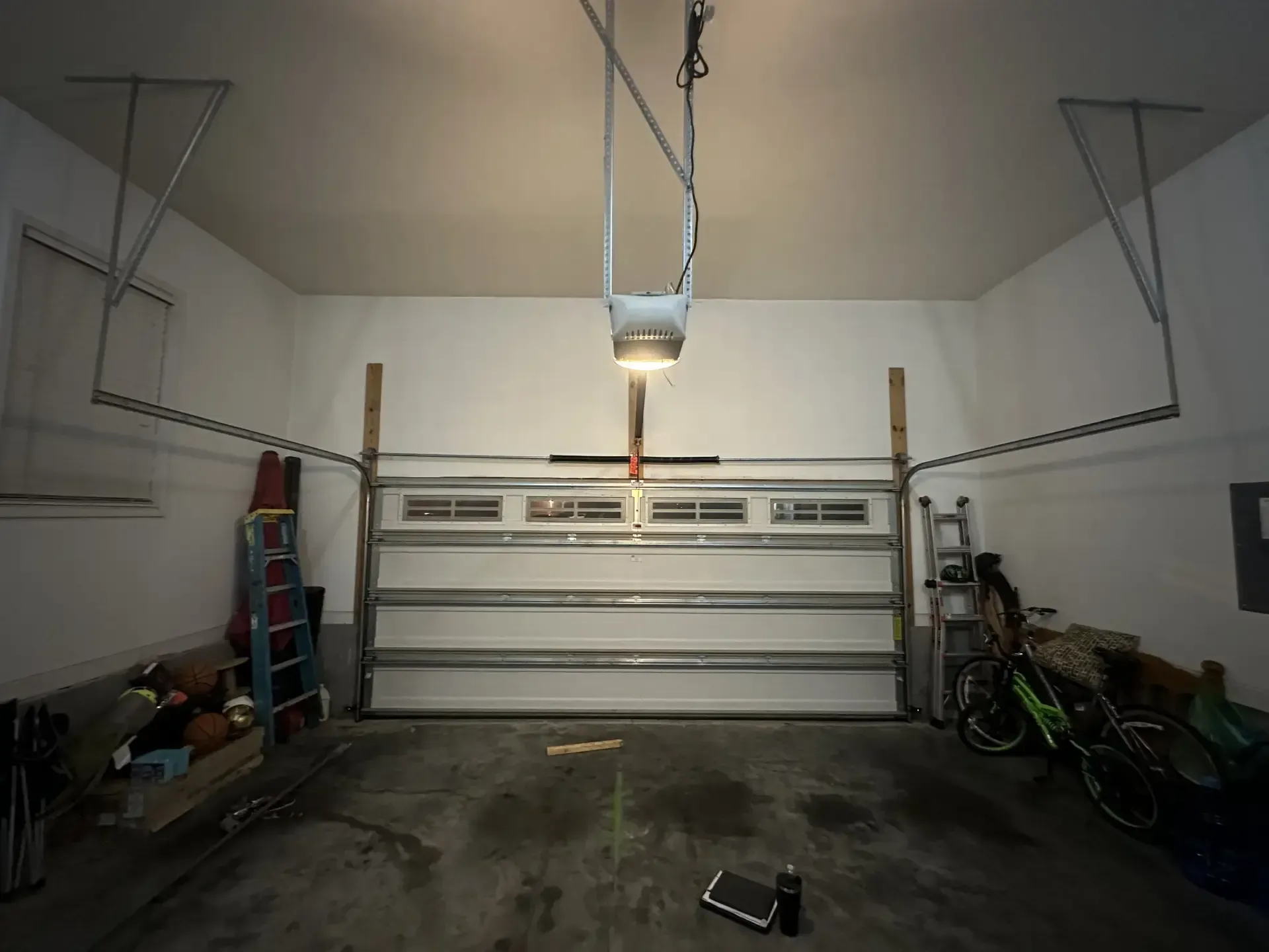 A garage with a garage door open and a light on the ceiling.