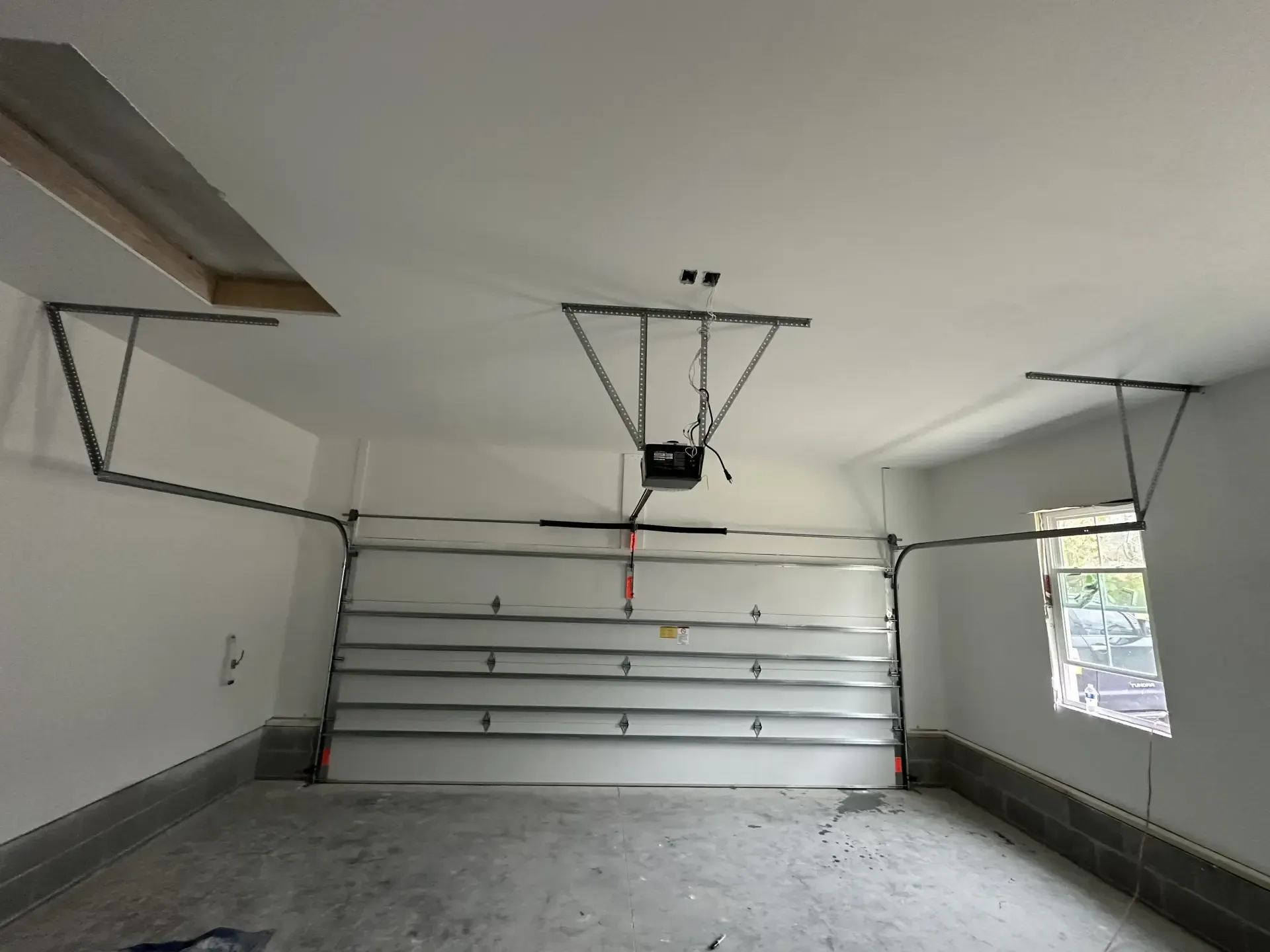 An empty garage with a garage door open and a window