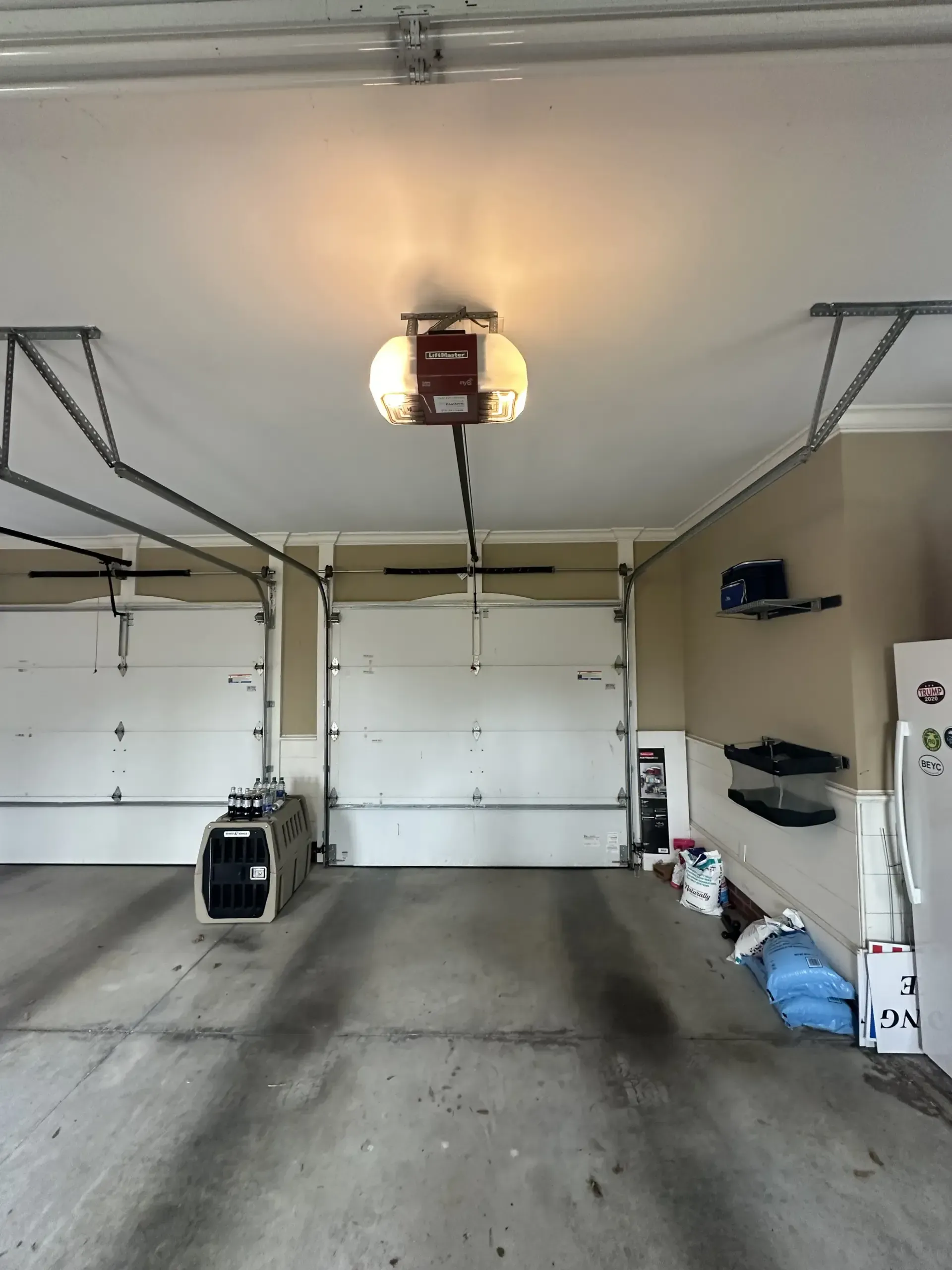 An empty garage with a garage door opener hanging from the ceiling.