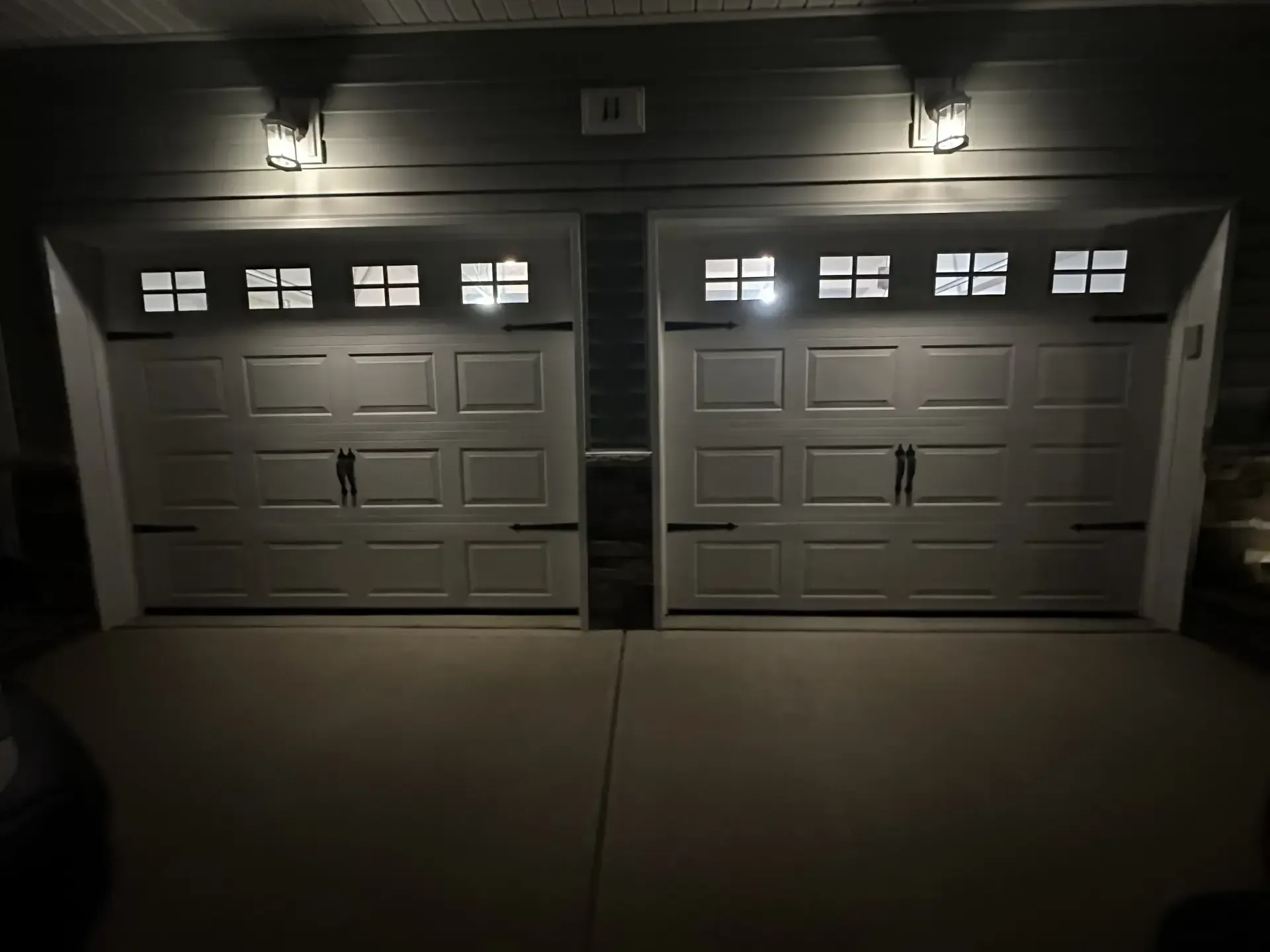 A couple of garage doors that are lit up at night.