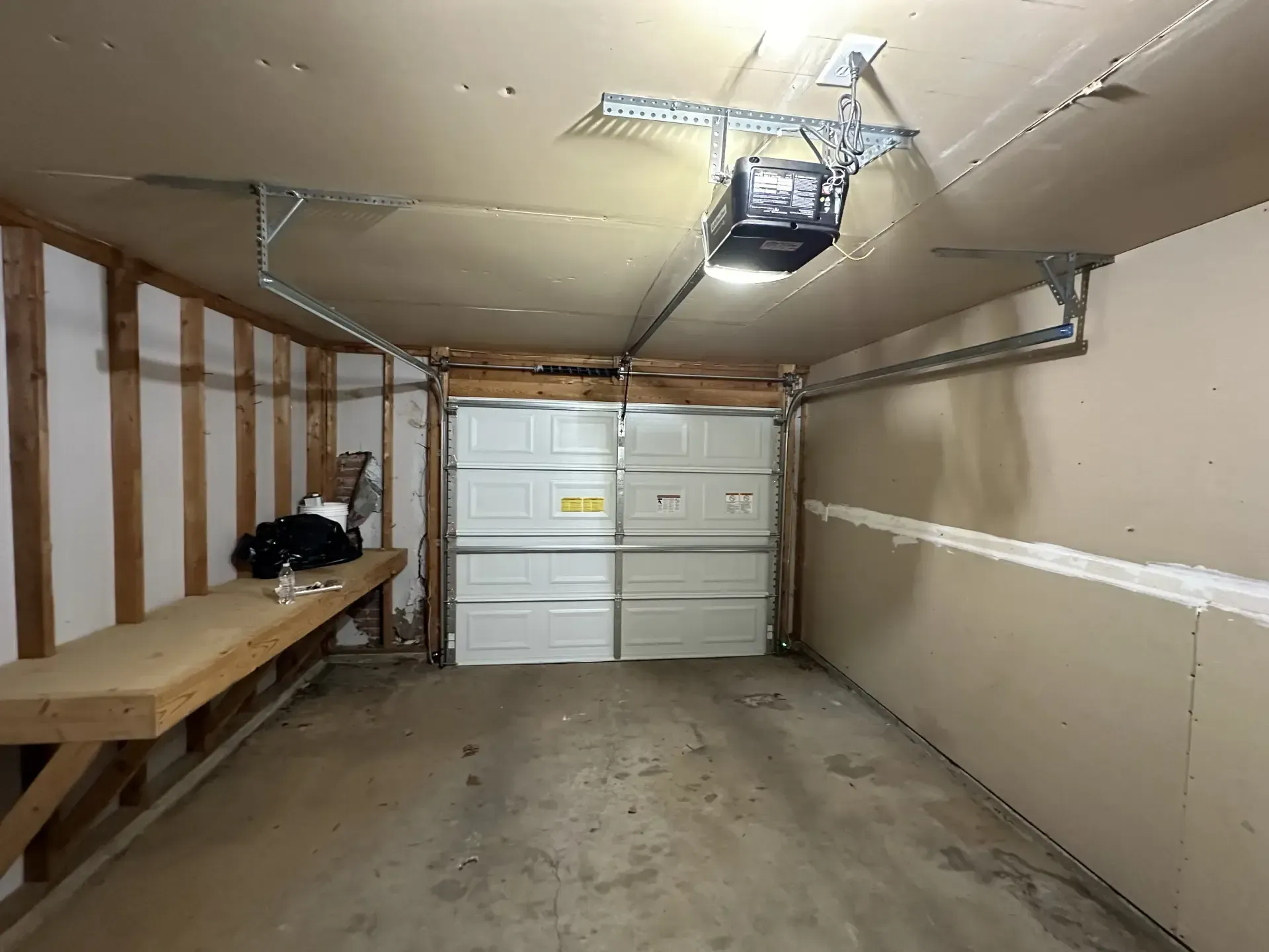 A garage with a garage door open and a light on the ceiling.
