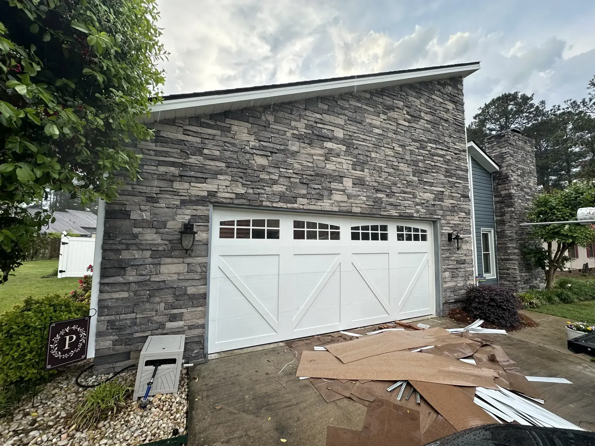 A white garage door is being installed on a stone house.