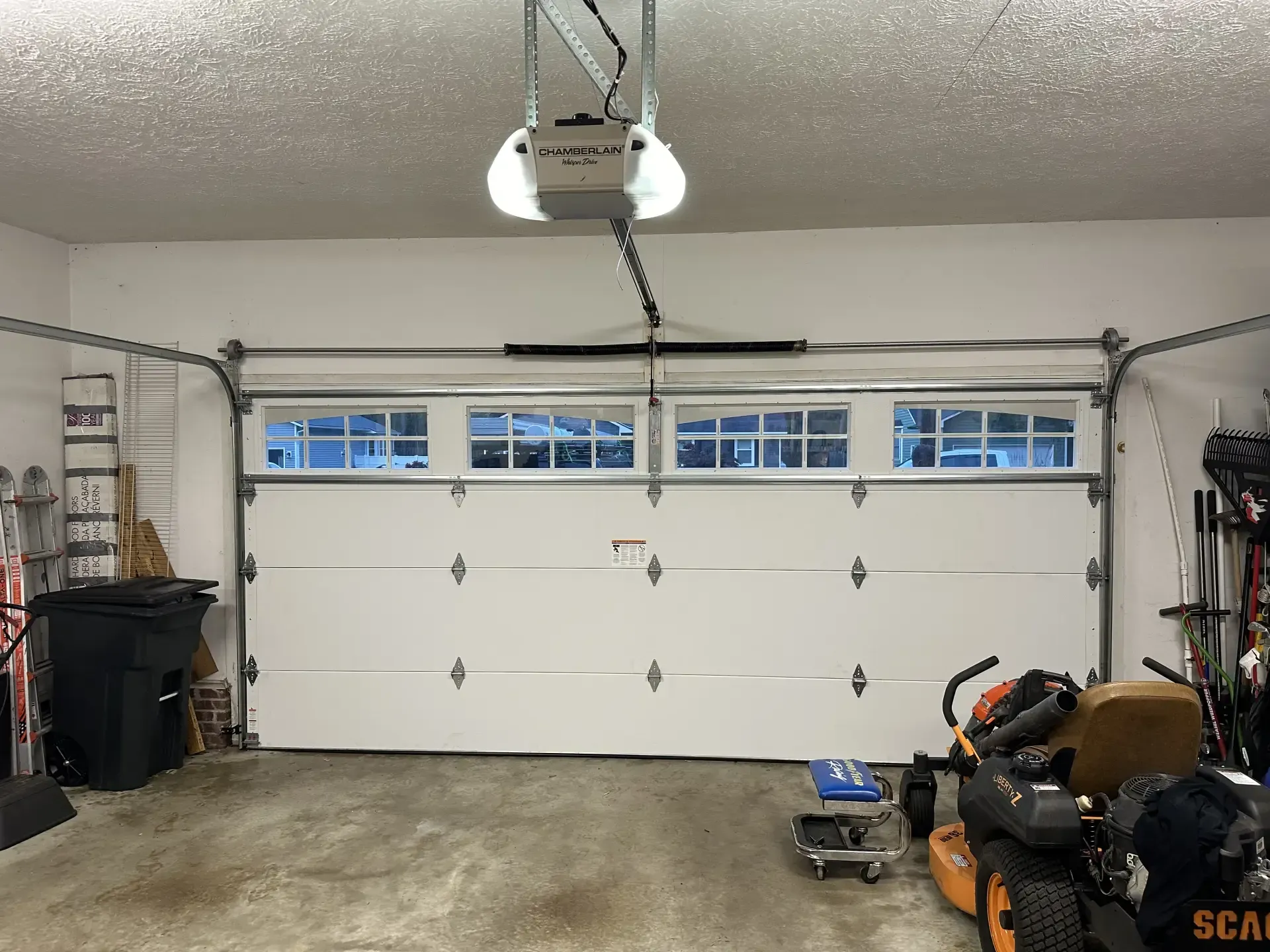 A garage with a white garage door and a lawn mower.