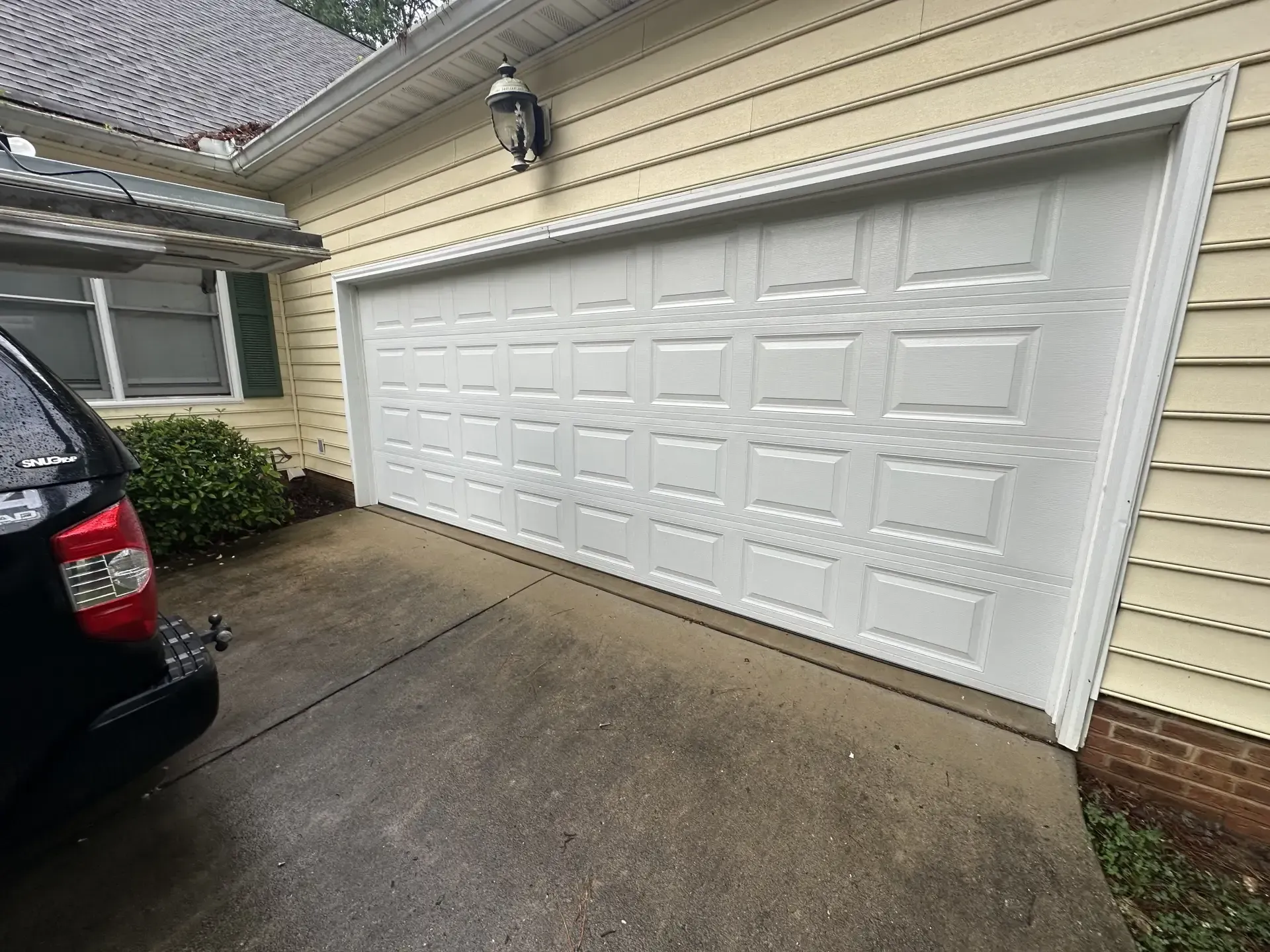 A car is parked in front of a white garage door.