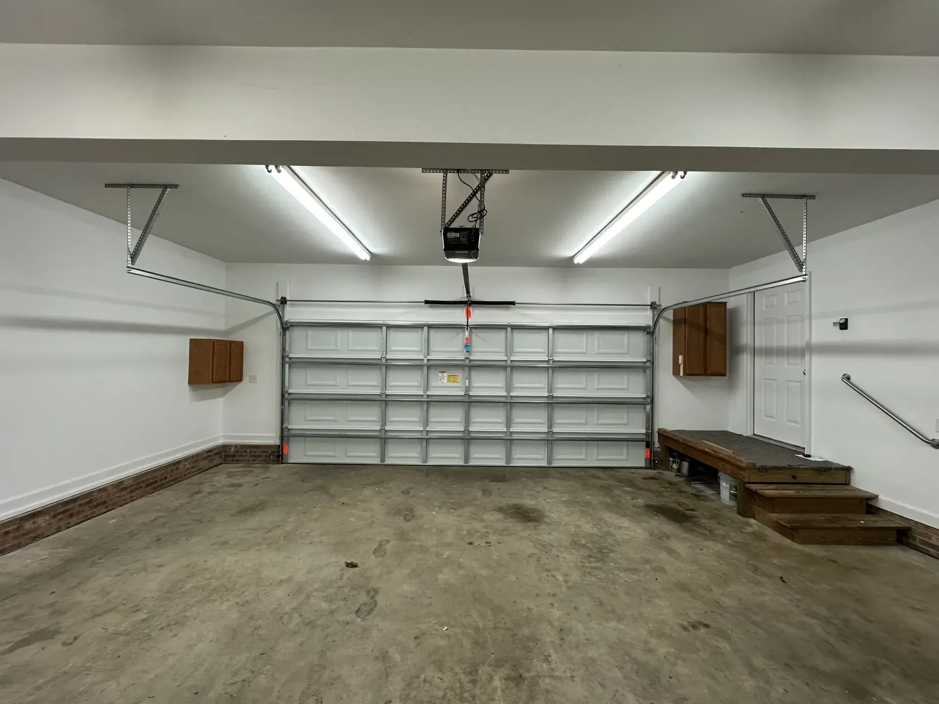 An empty garage with a garage door open and a ceiling fan.