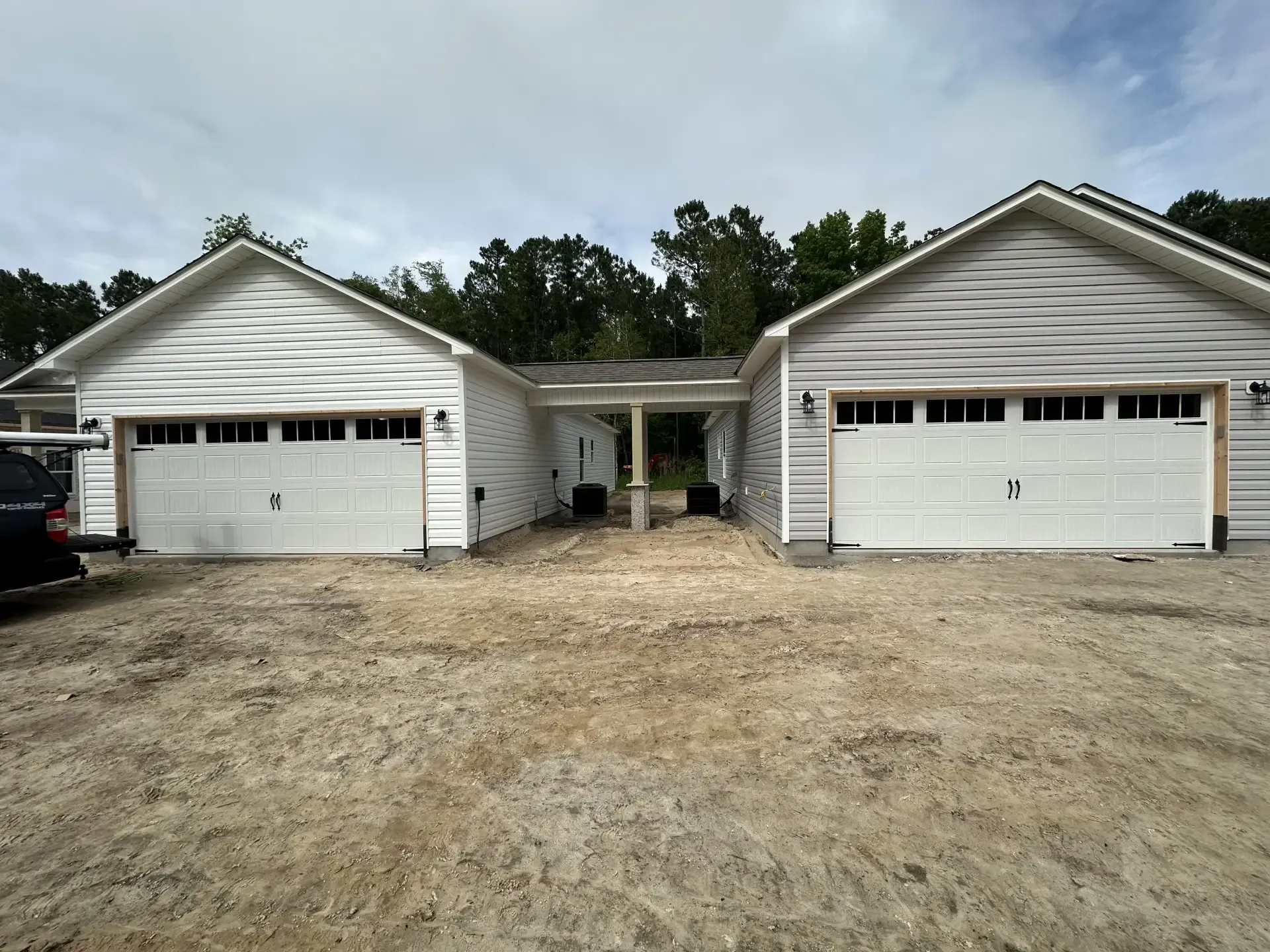 Two white garages with a black truck parked in front of them