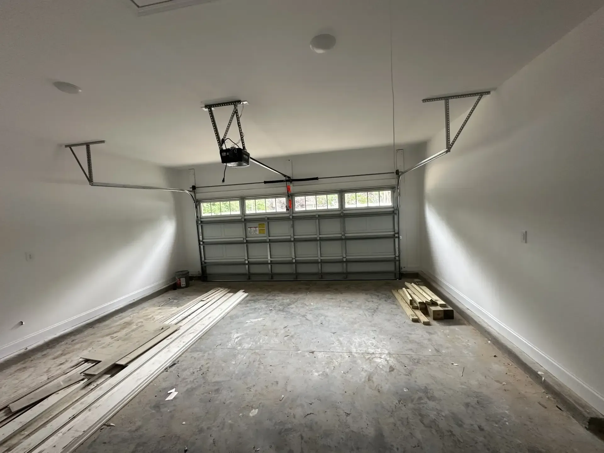 An empty garage with a garage door open and a ceiling fan.