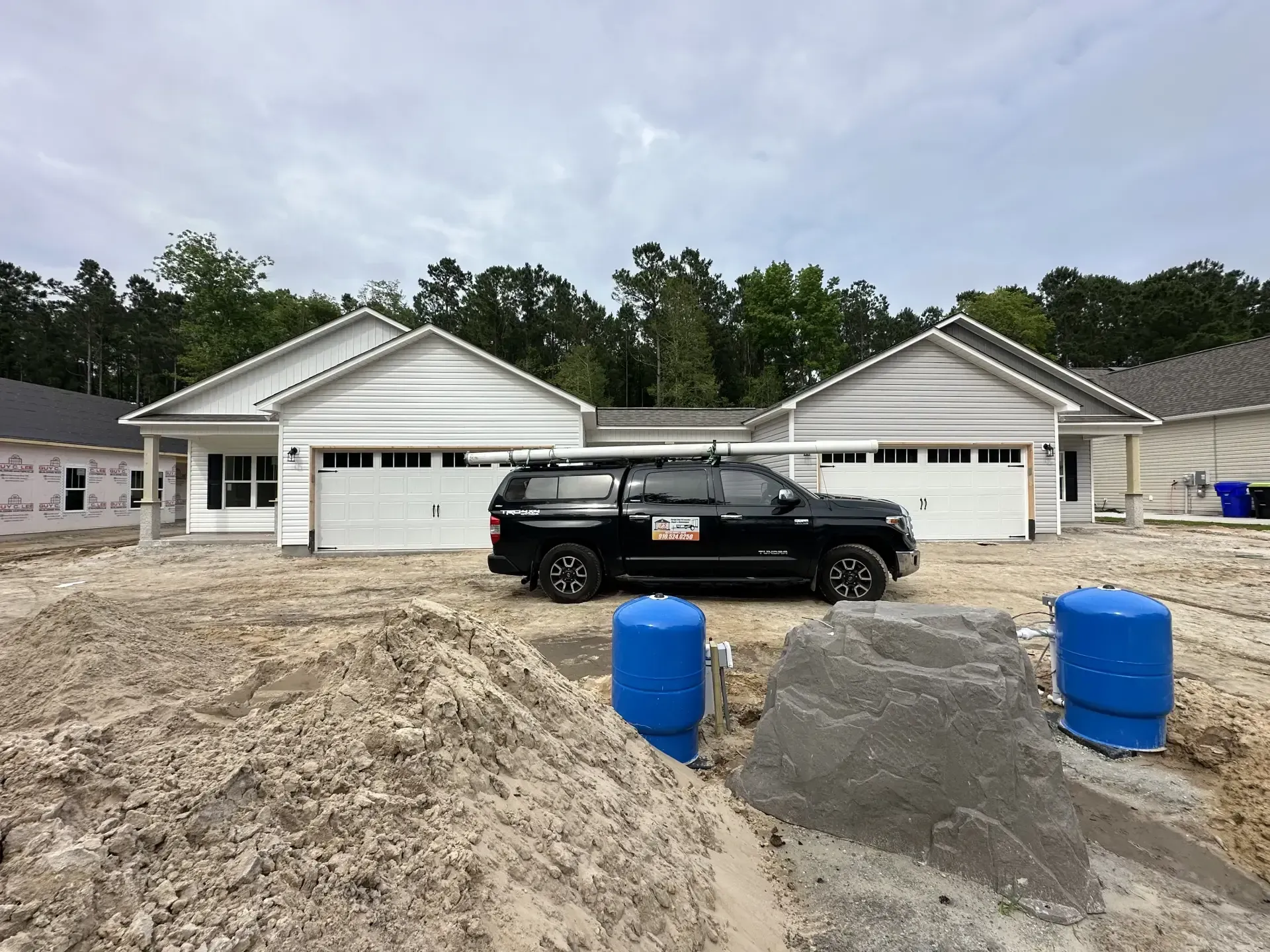 A black suv is parked in front of a house under construction.