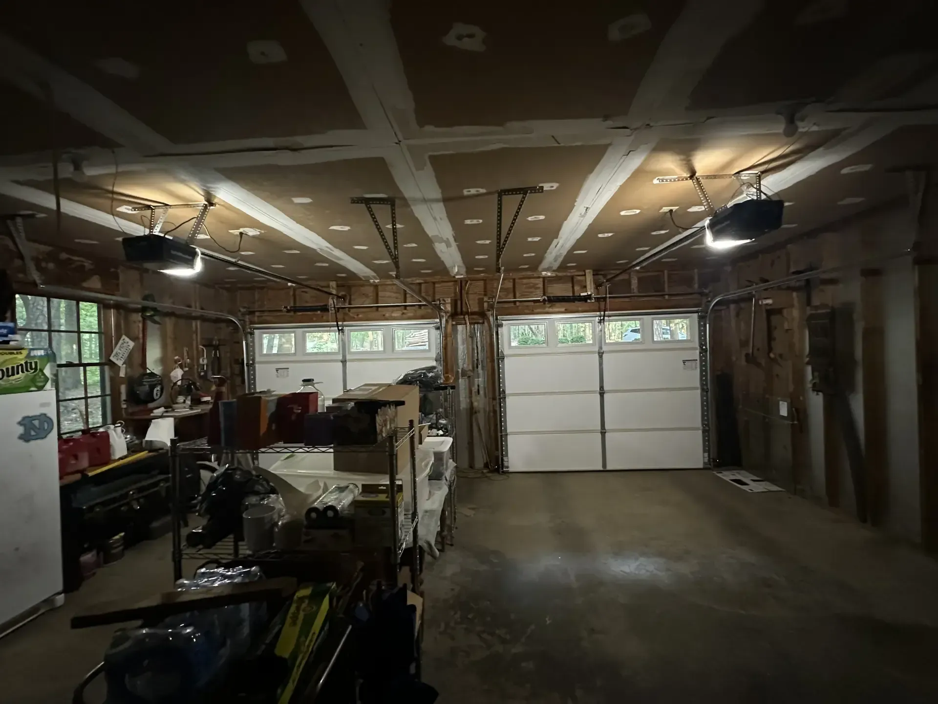 A garage with two garage doors and a refrigerator.