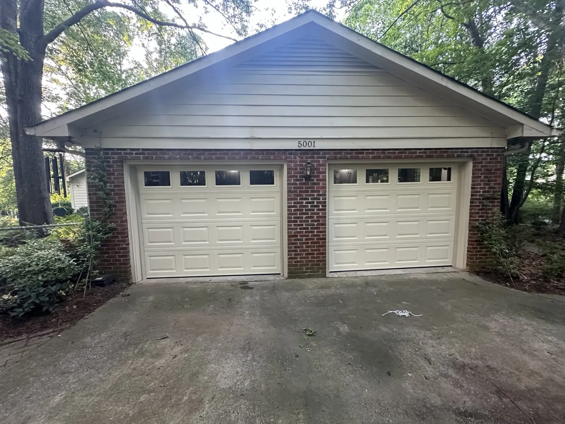 A garage with two white garage doors and a brick wall.