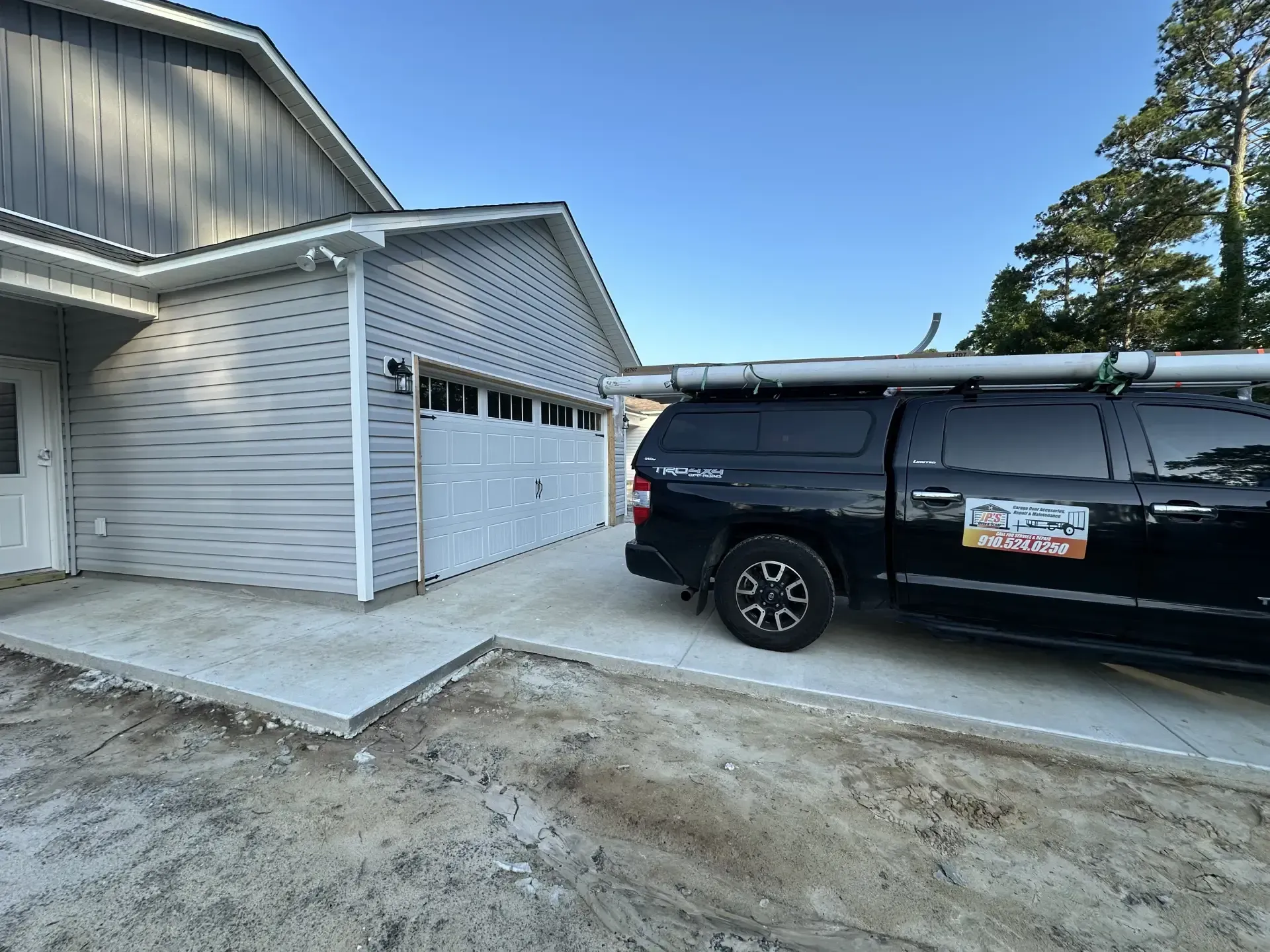 A black truck is parked in front of a garage door.