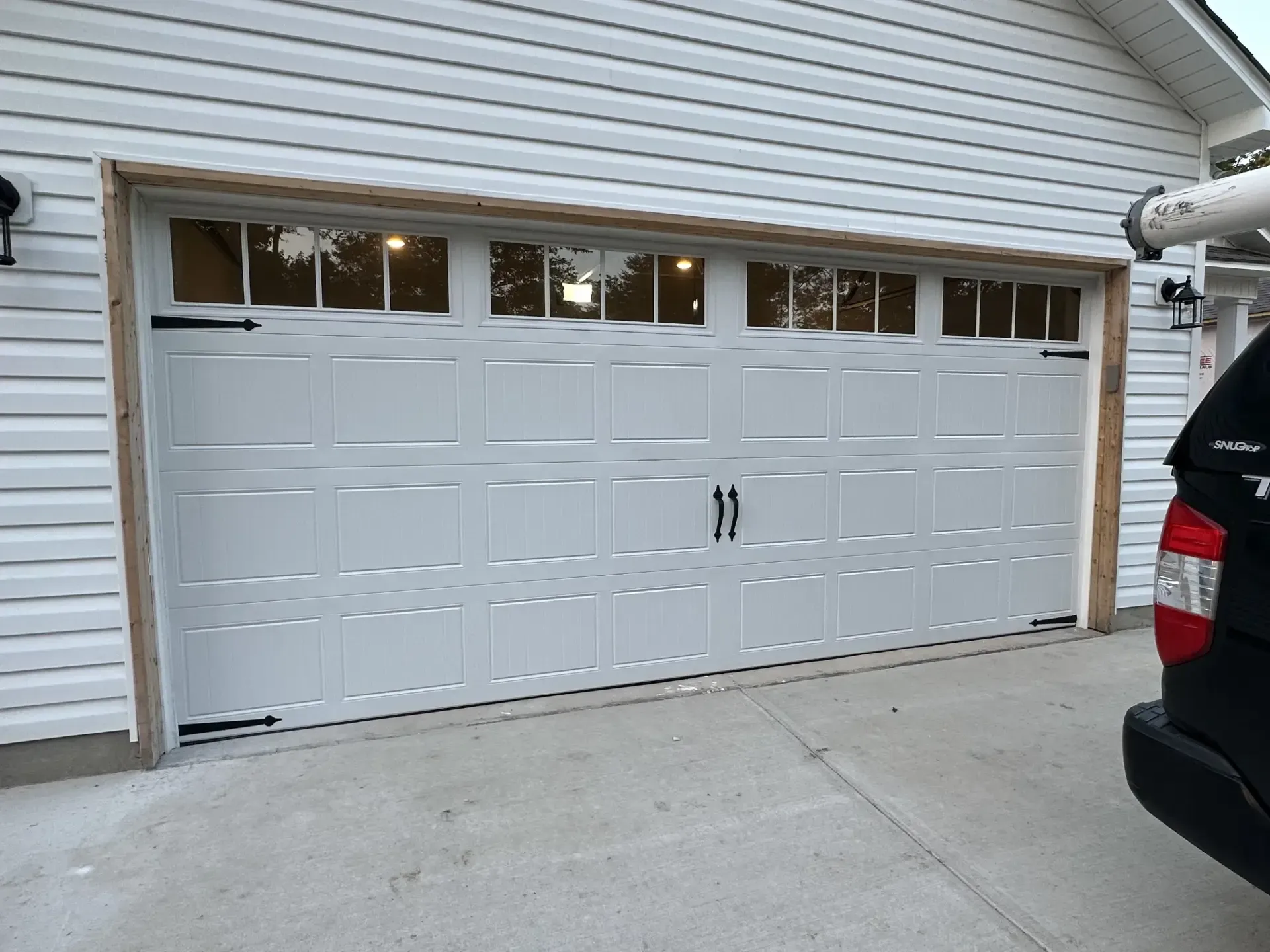 A car is parked in front of a white garage door