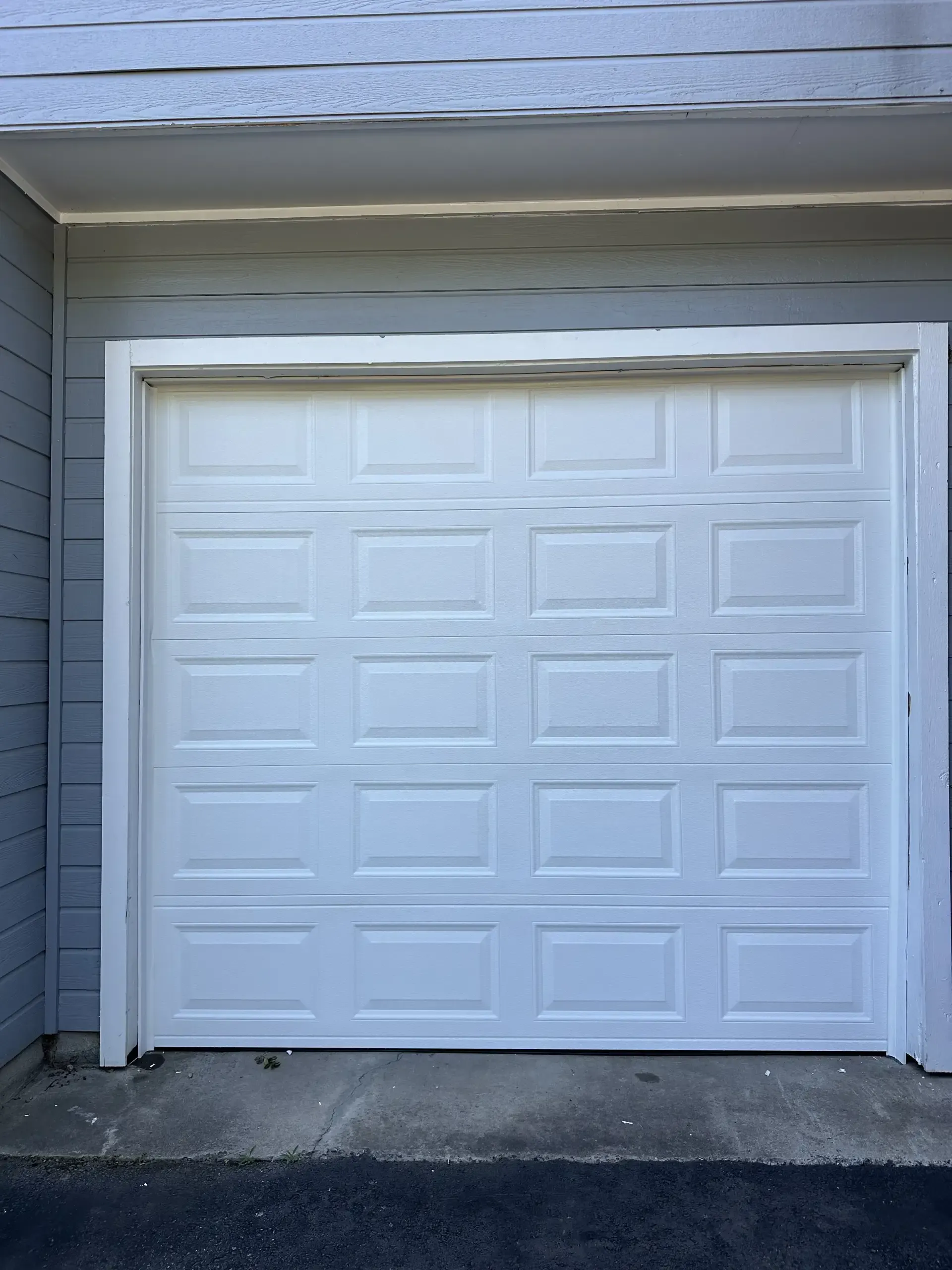 A white garage door is open on the side of a house.