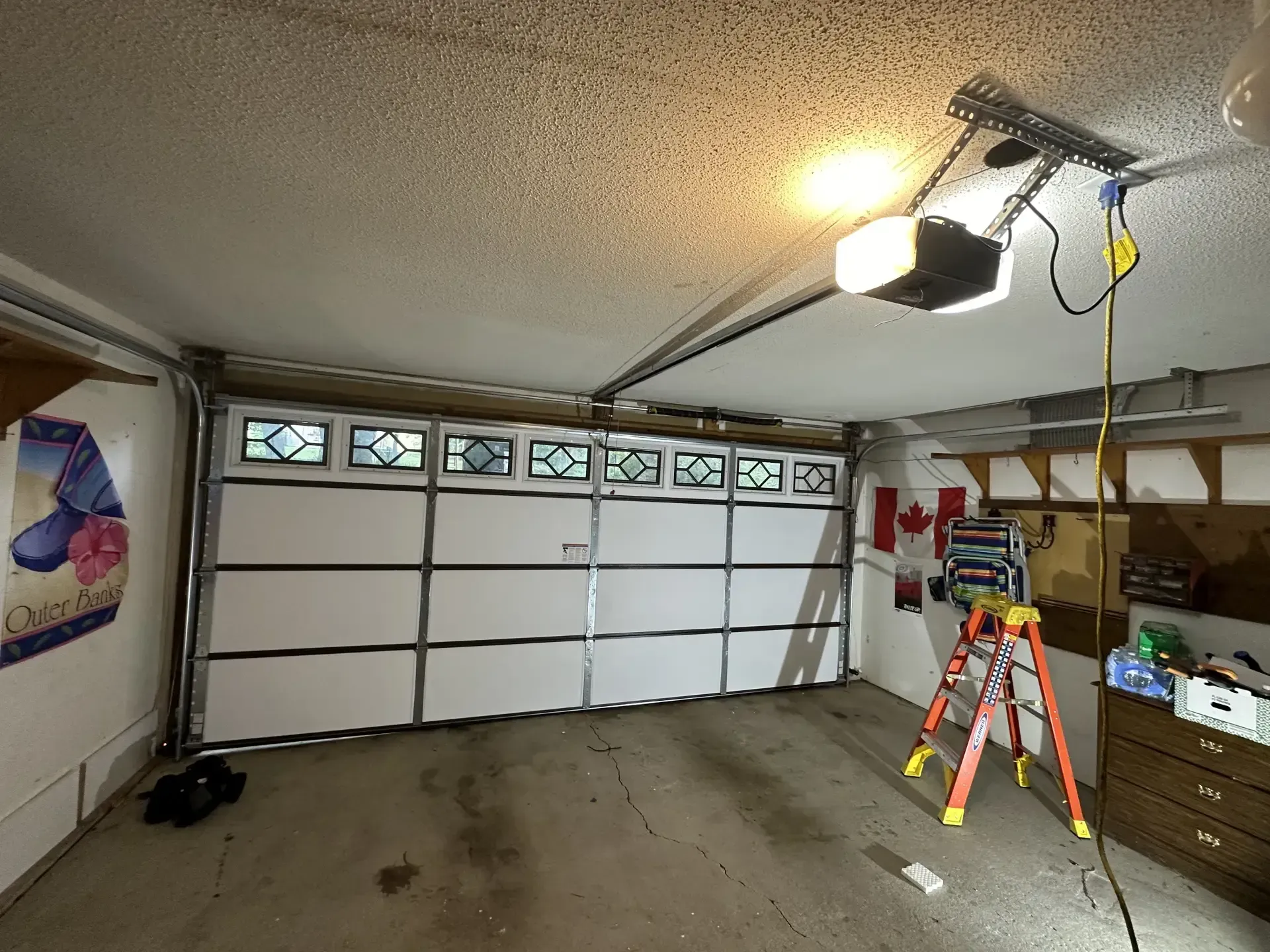 A garage with a ladder and a garage door open.