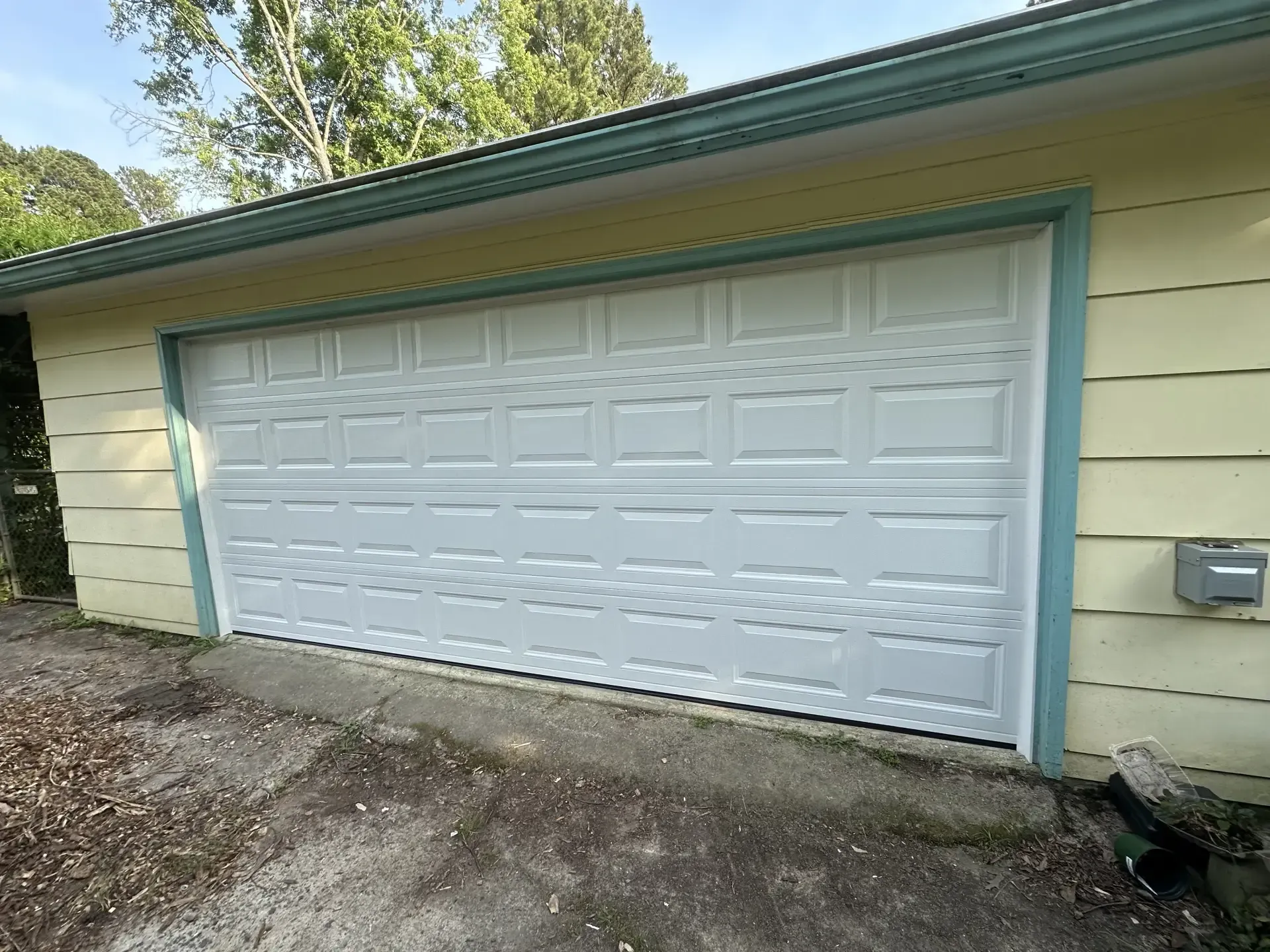 A white garage door is sitting on the side of a house.