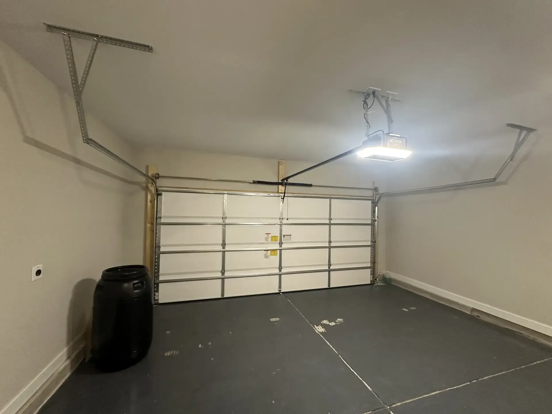 A garage with a garage door open and a tire on the floor.