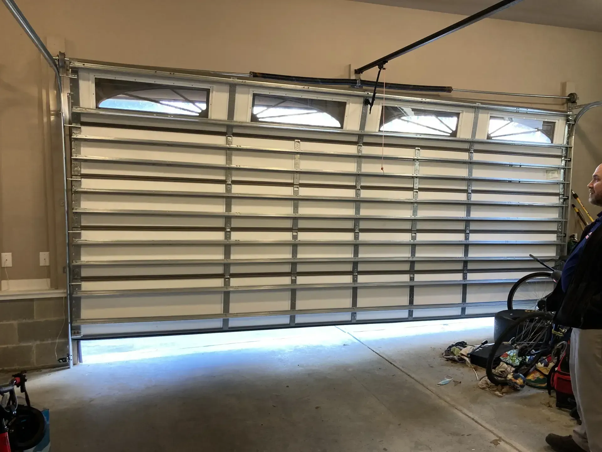 A man is standing in front of a garage door that is open.