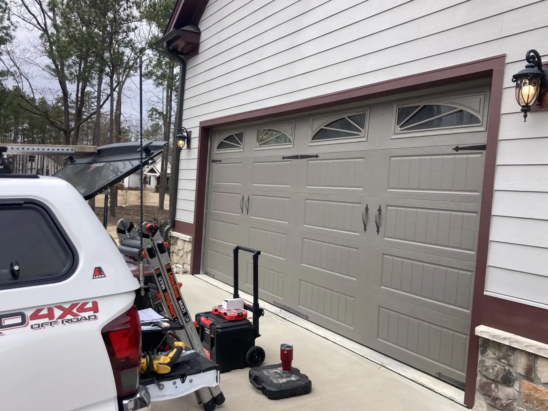 A white truck is parked in front of a garage door.
