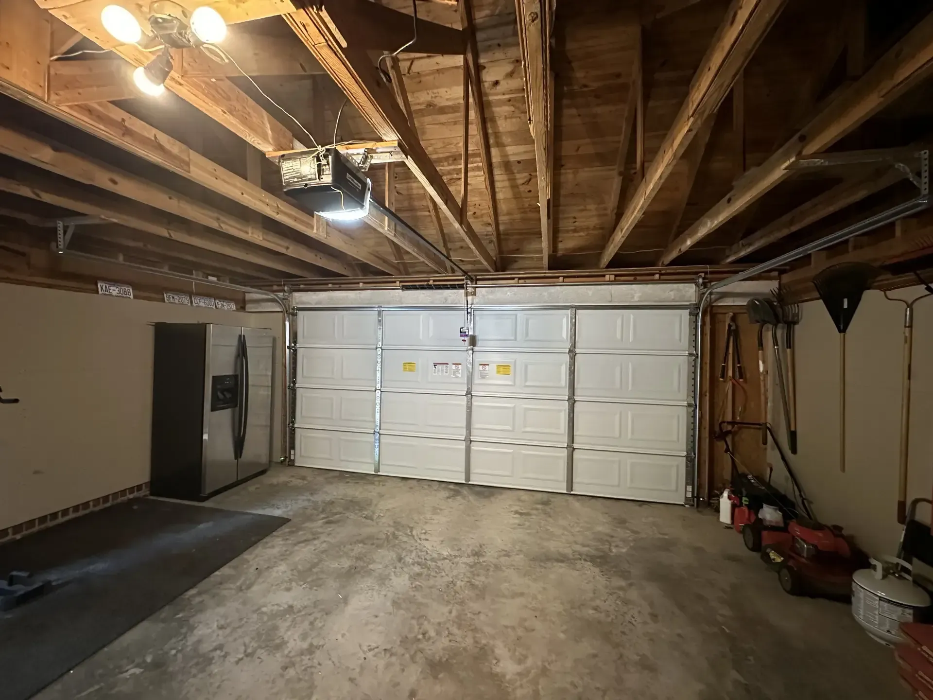 A garage with a large white garage door and a refrigerator.