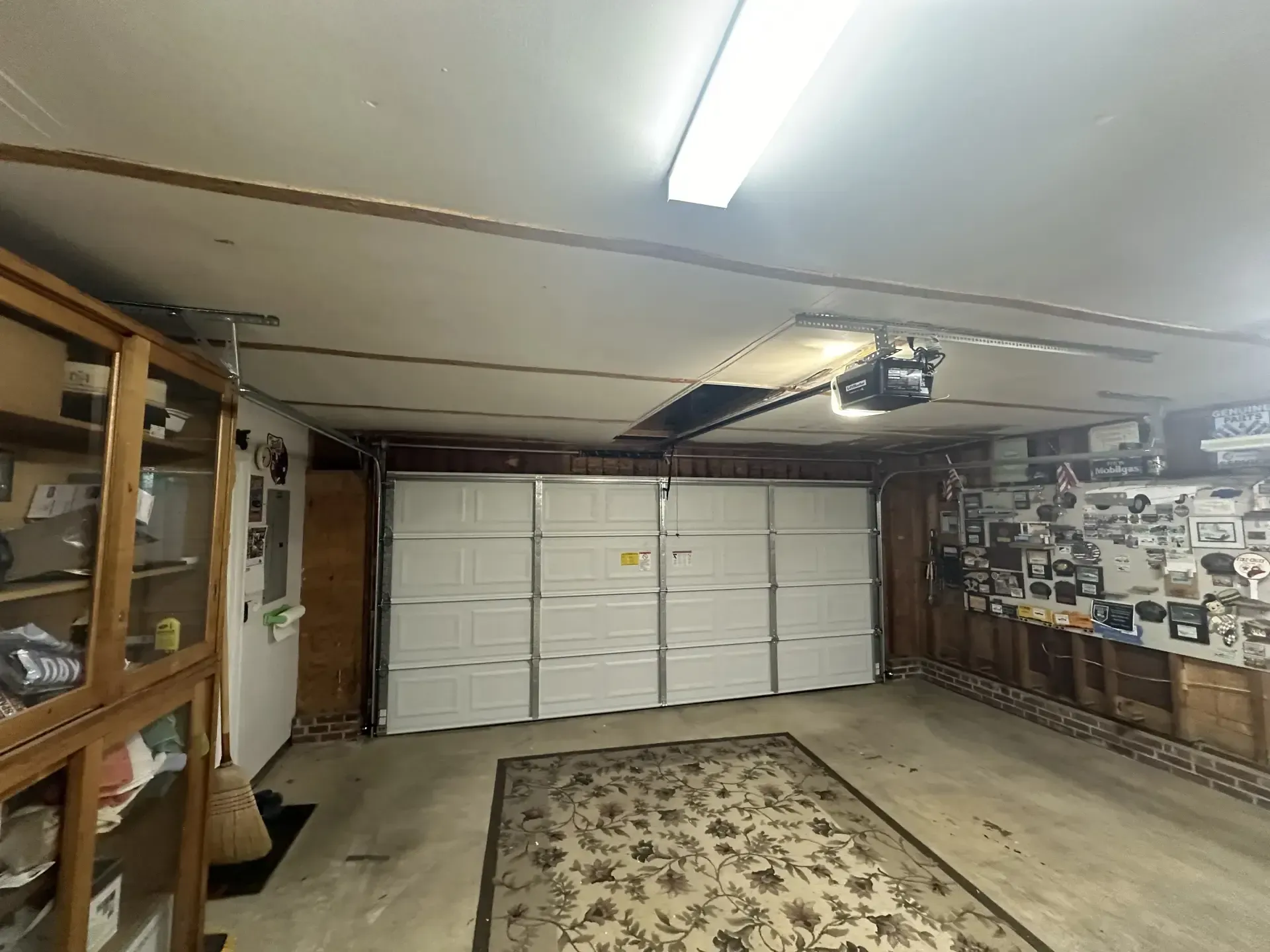 A garage with a white garage door and a rug on the floor.