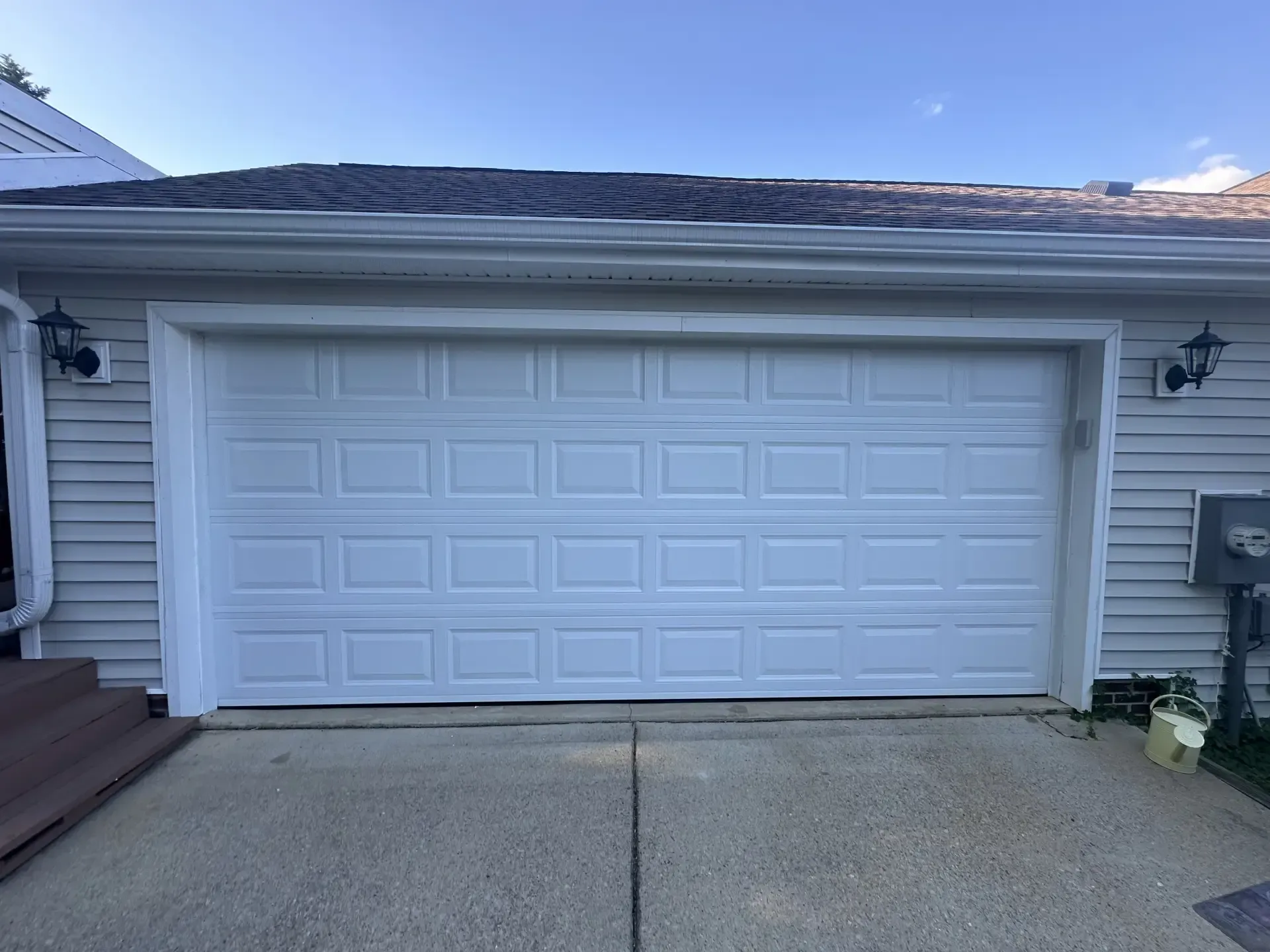 A white garage door is open in front of a house
