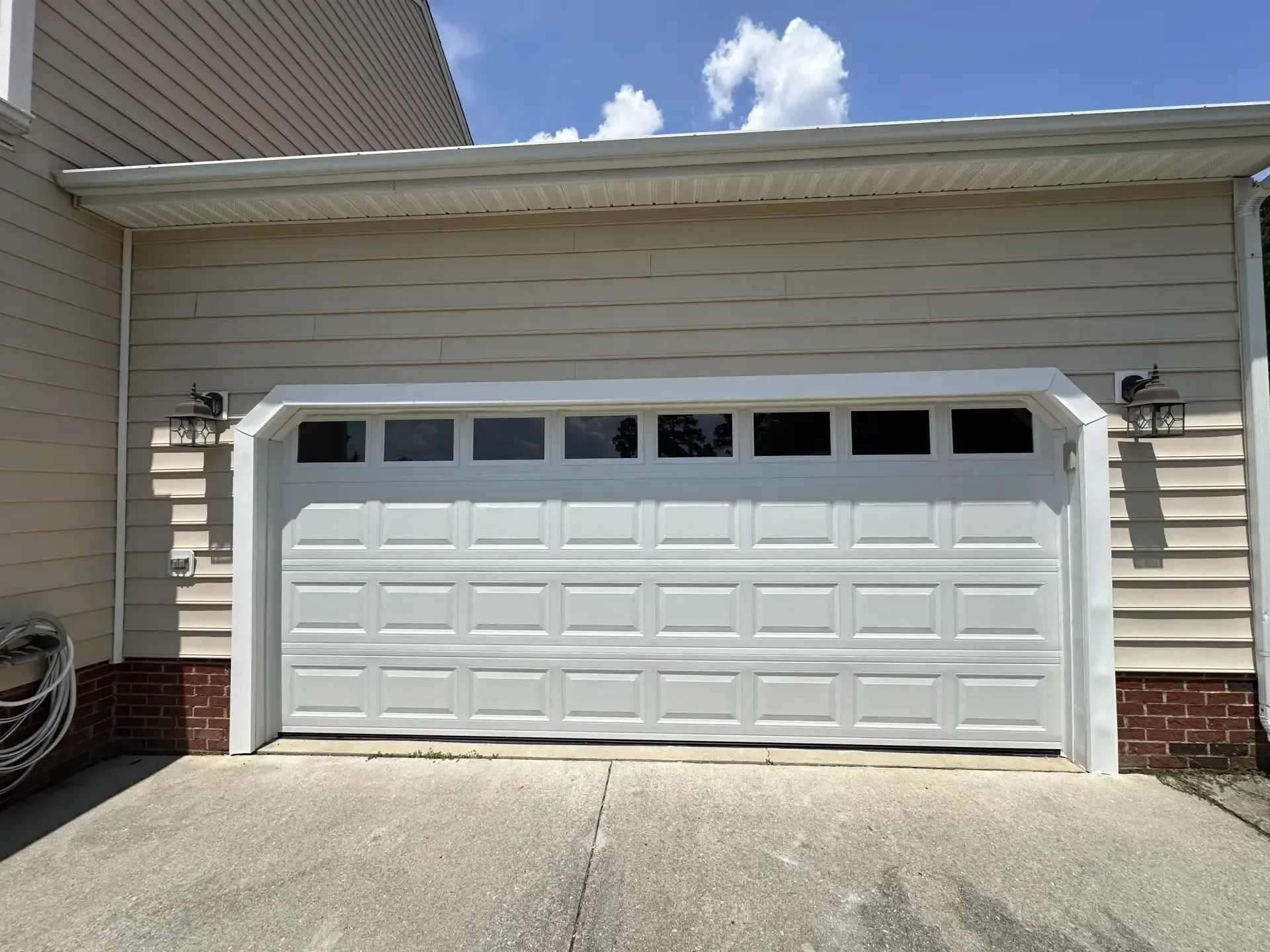 A white garage door is open in front of a house.
