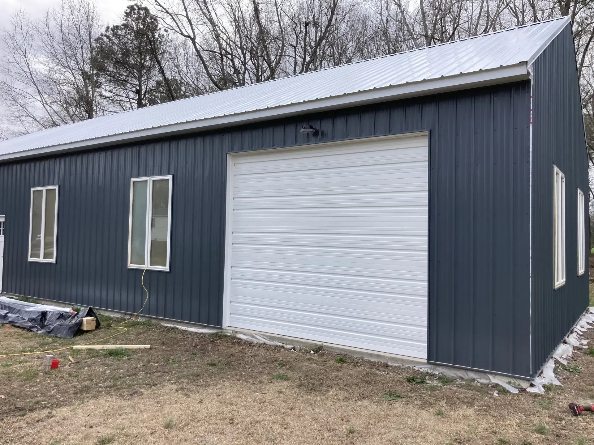 A black metal building with a white garage door and windows.