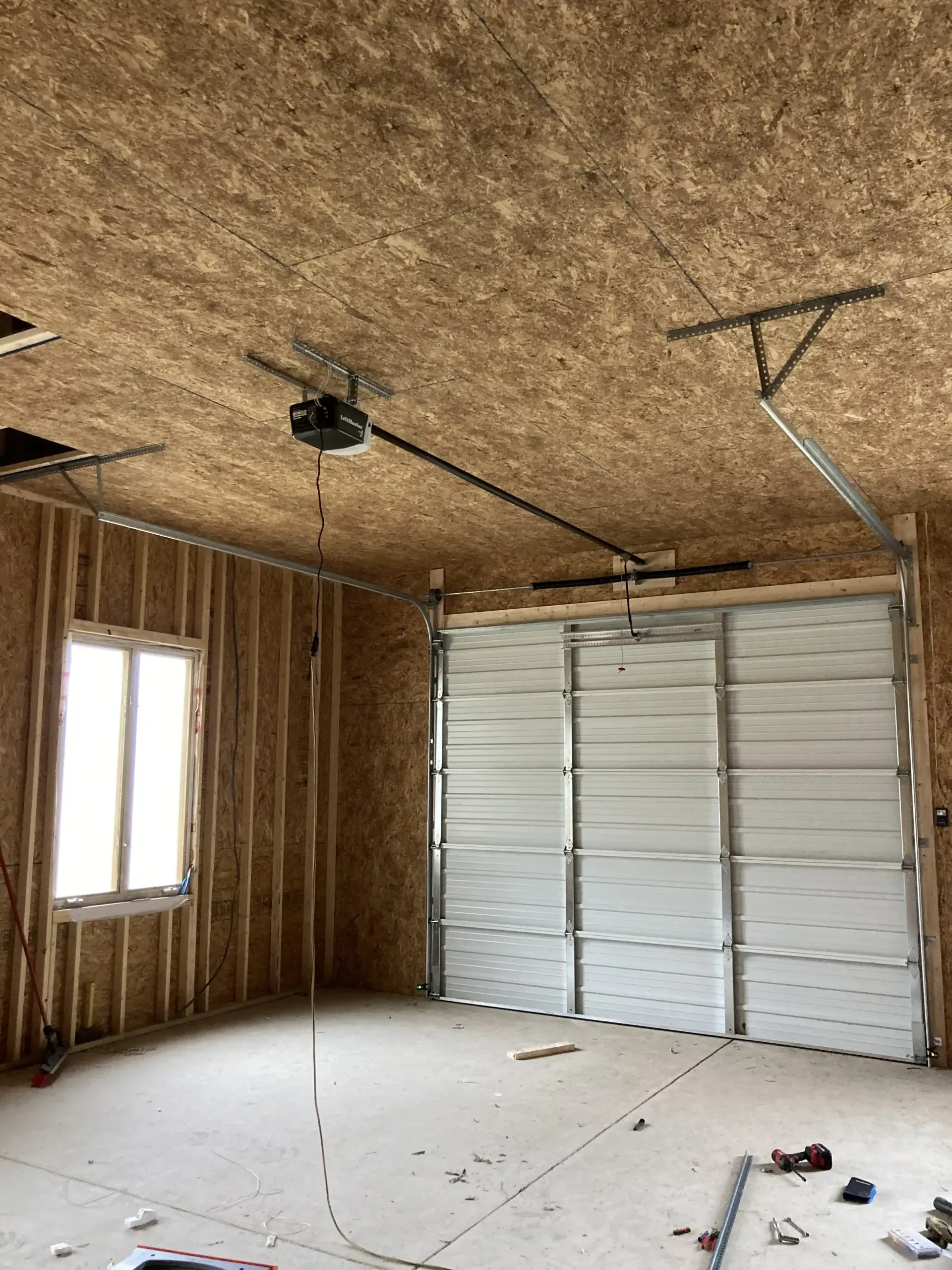 A garage with a garage door open and a ceiling fan.