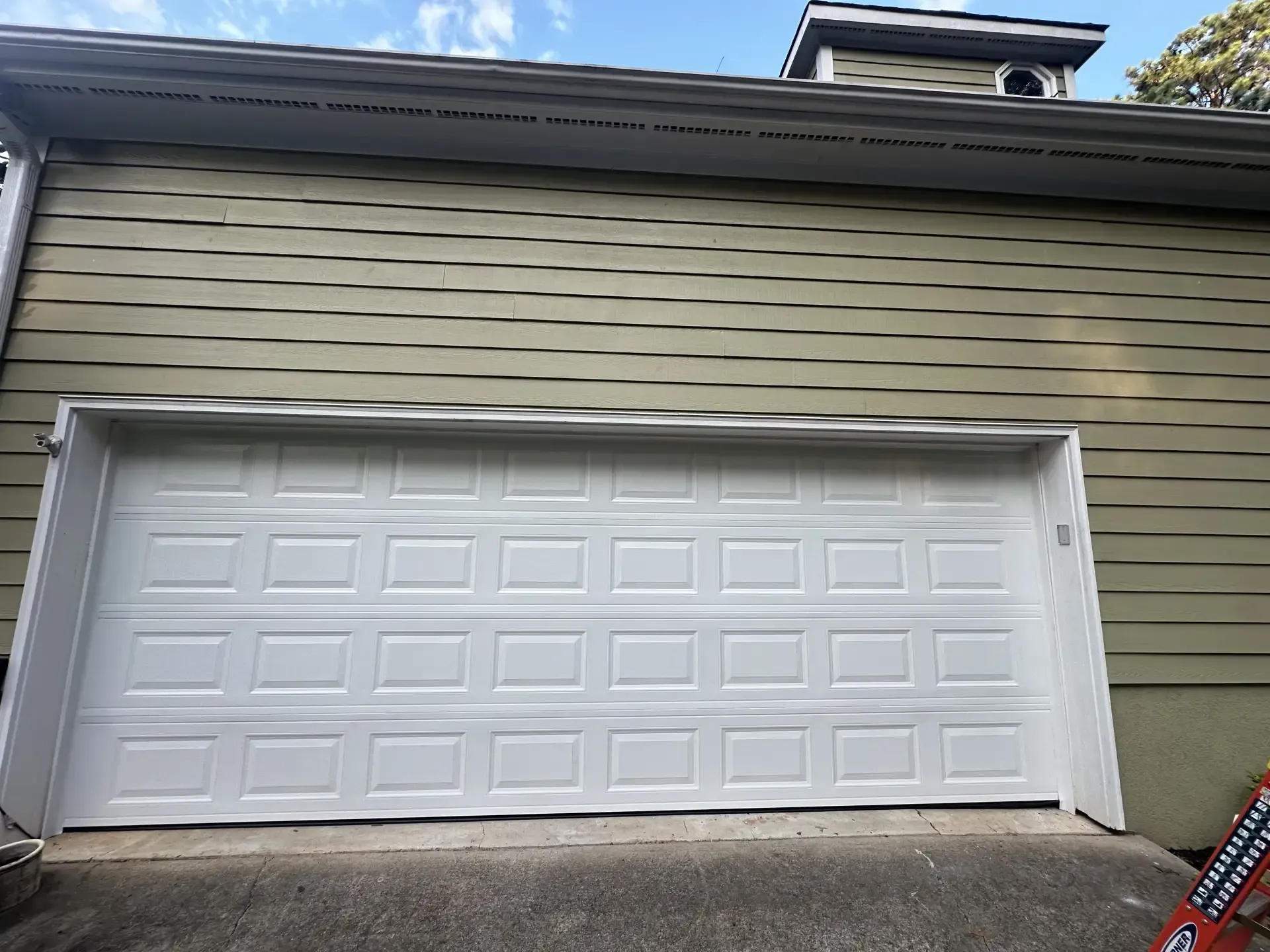 A white garage door is sitting on the side of a house.