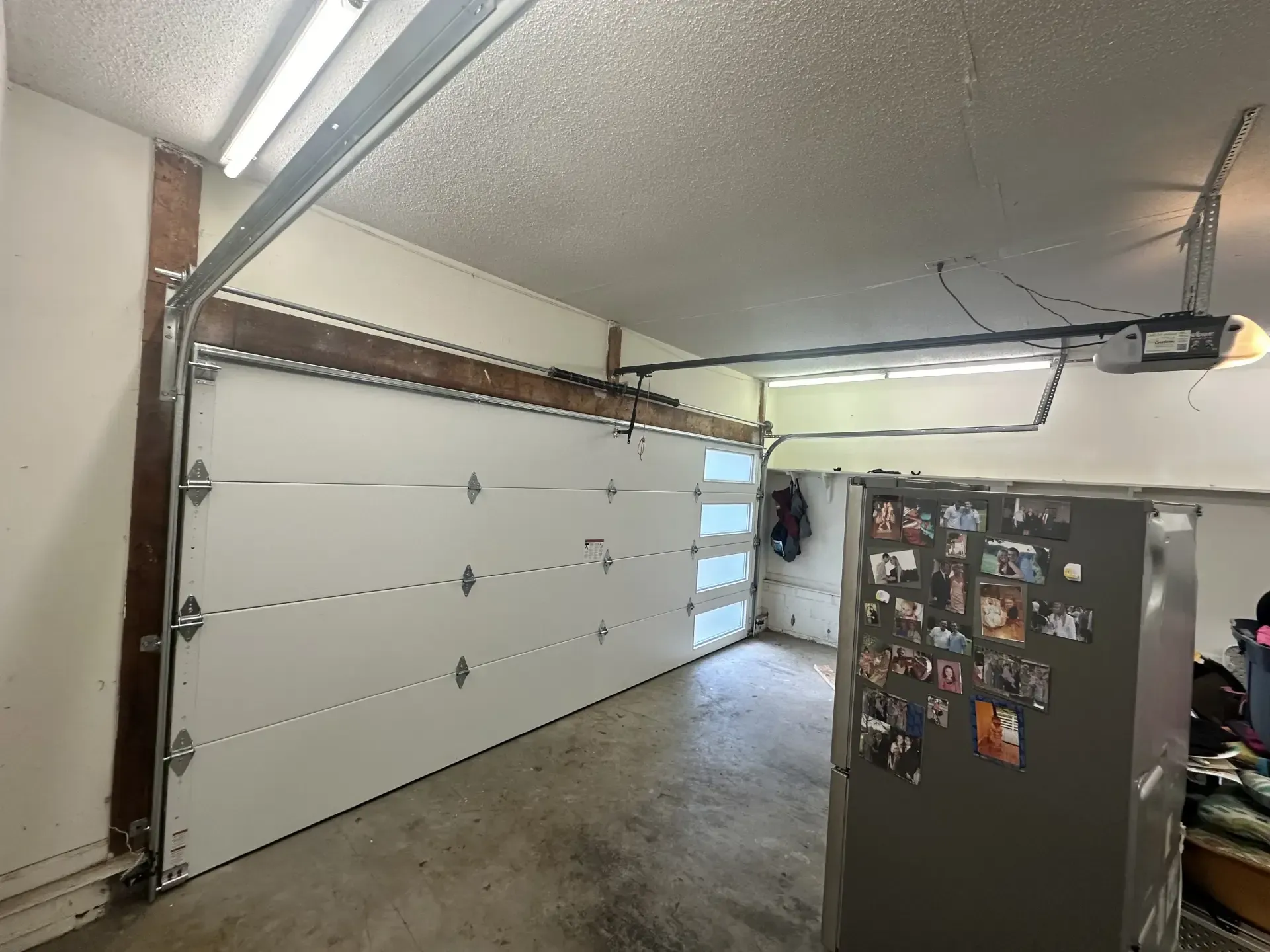 A garage with a garage door open and a refrigerator.