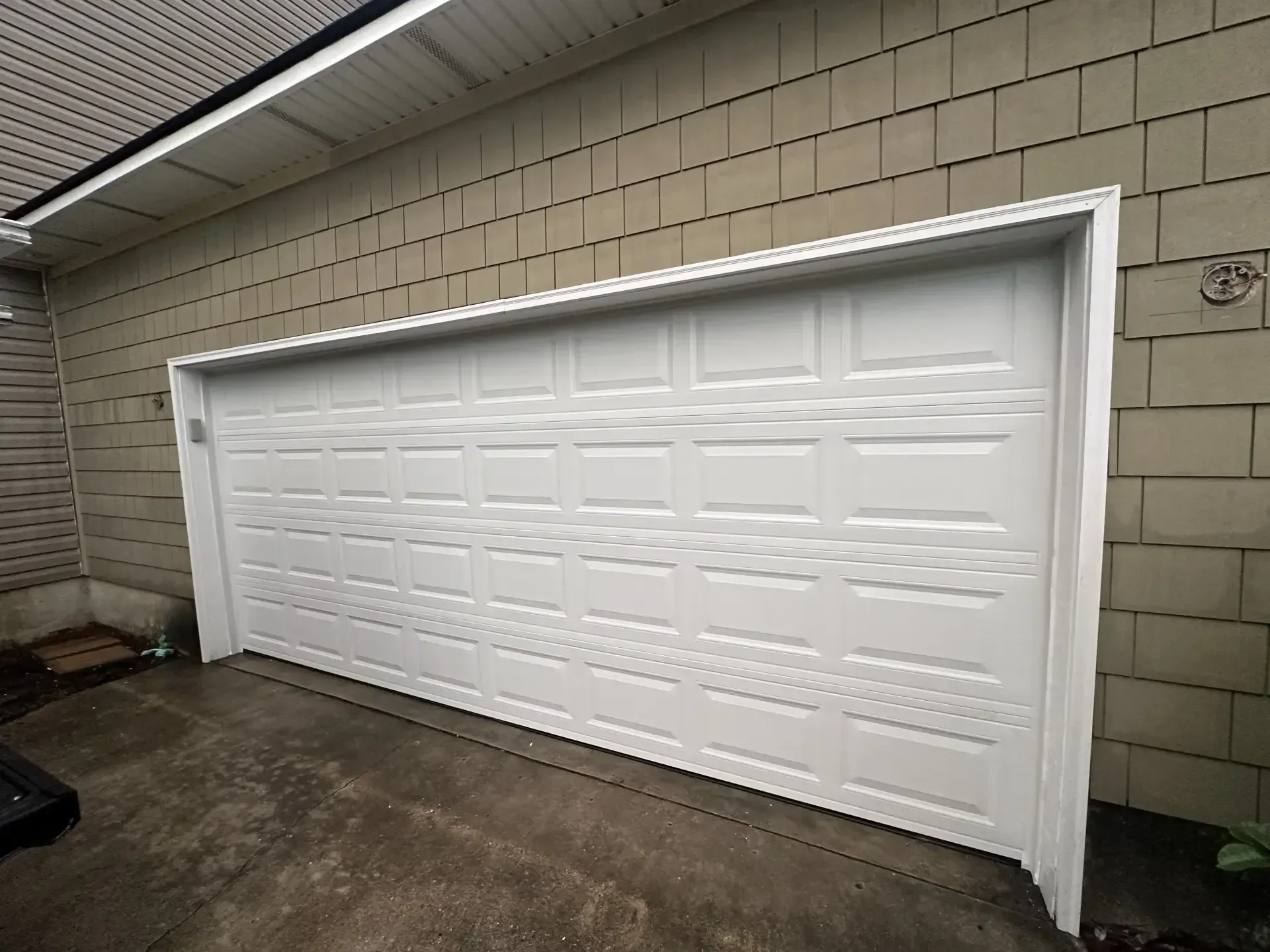 A white garage door with a brick wall behind it
