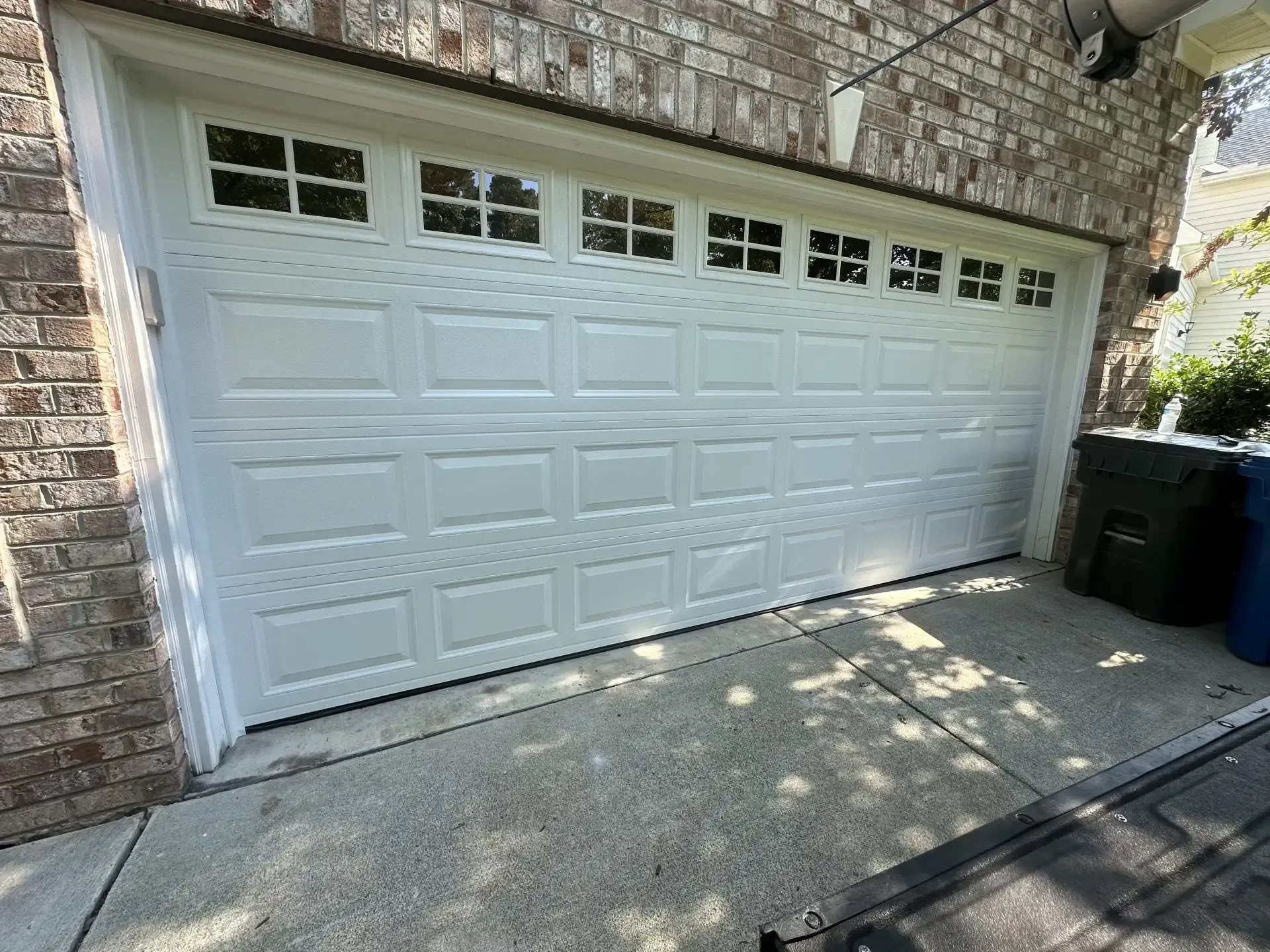 A white garage door is sitting in front of a brick building.