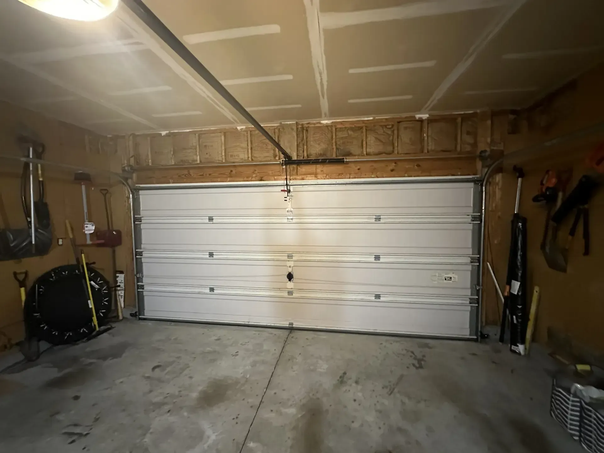 A garage with a broken garage door and tools on the wall.