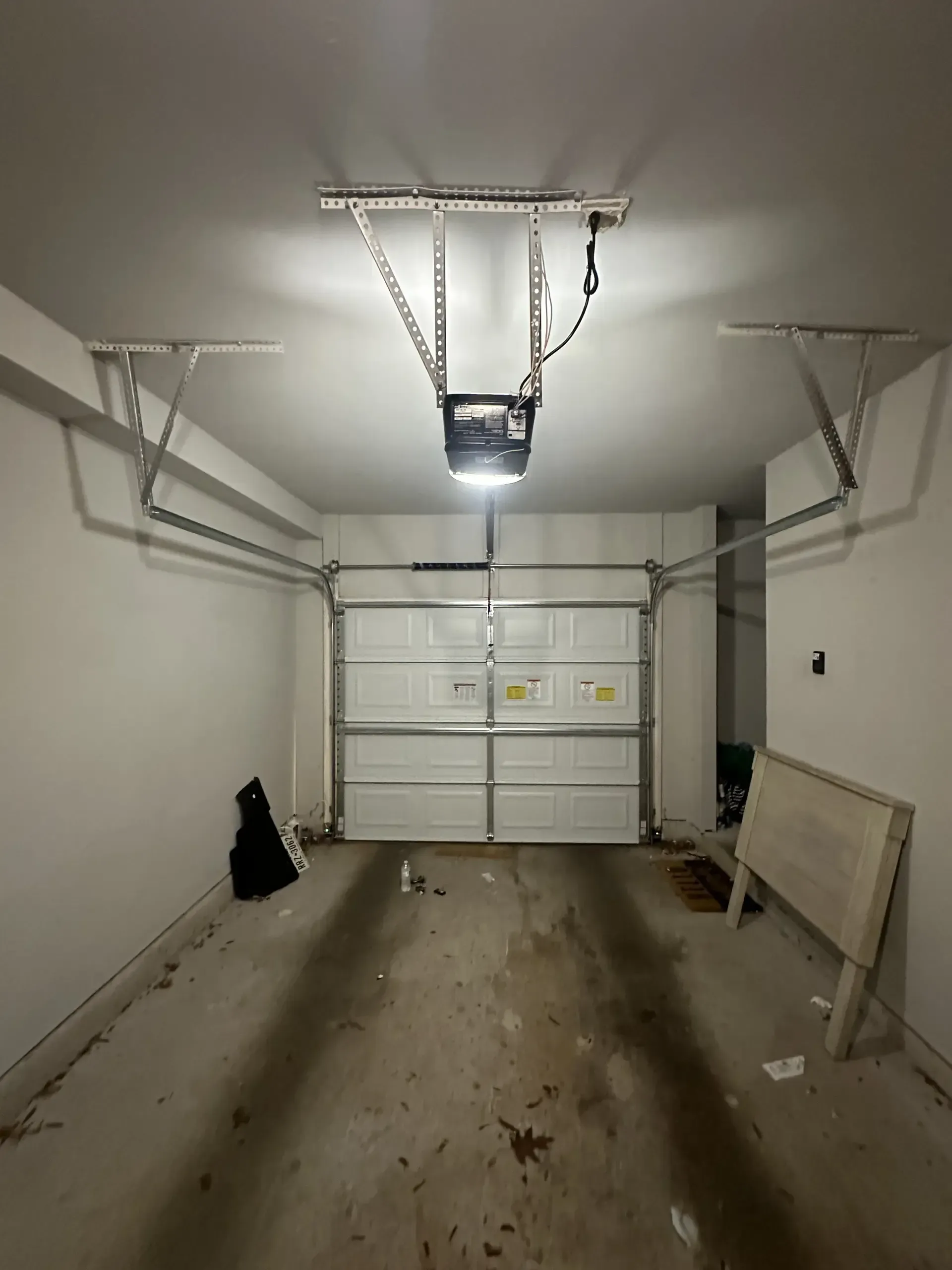 An empty garage with a garage door open and a light on the ceiling.