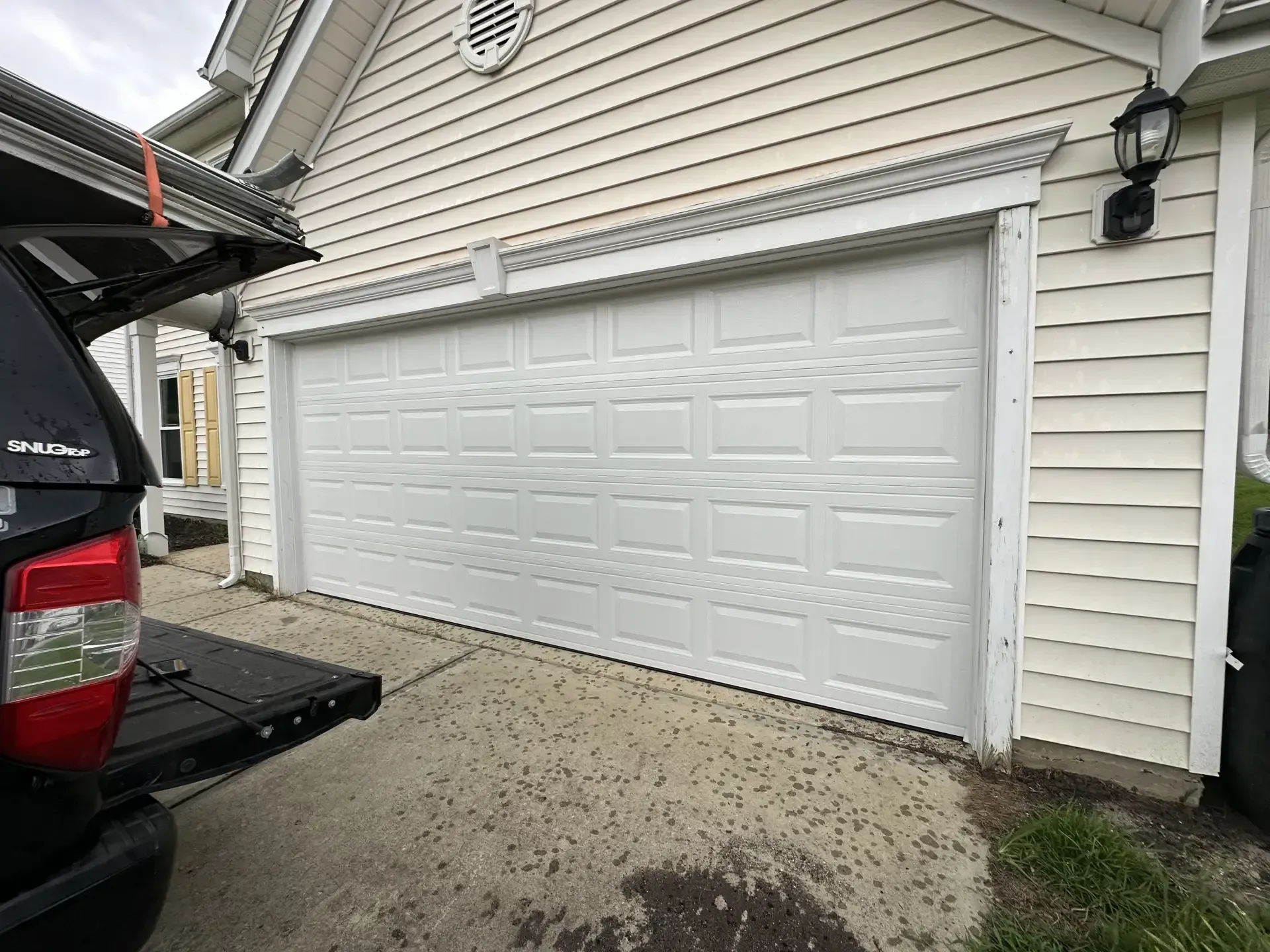 A truck is parked in front of a white garage door.