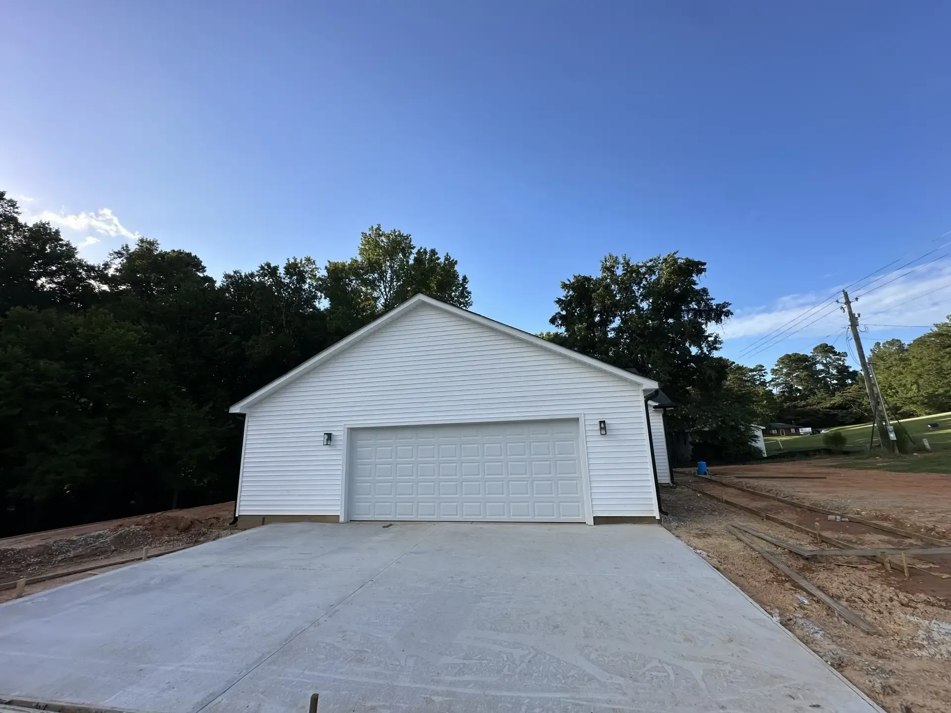 A white garage with a concrete driveway in front of it