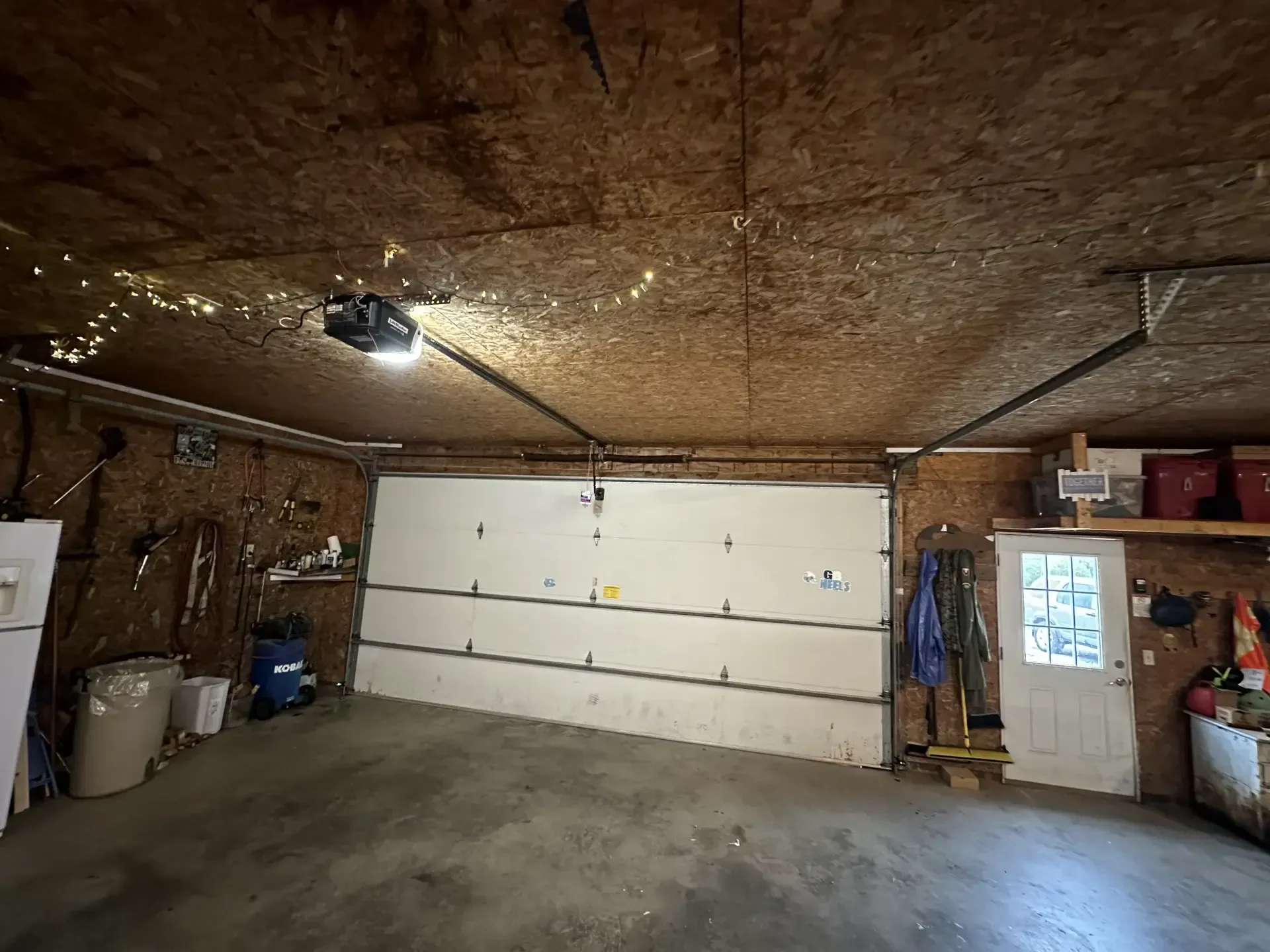 A garage with a garage door open and a light on the ceiling.