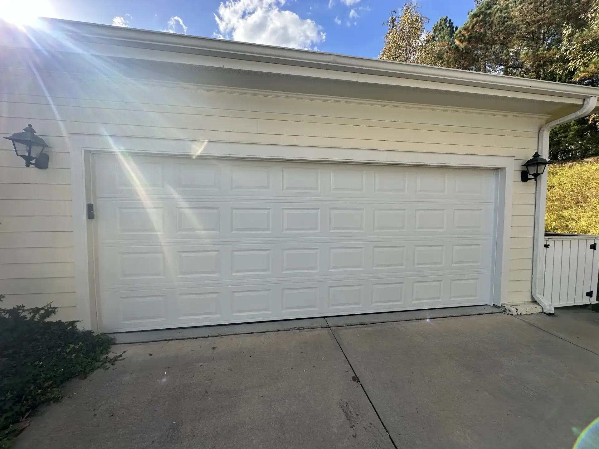 A white garage door is open on a sunny day.