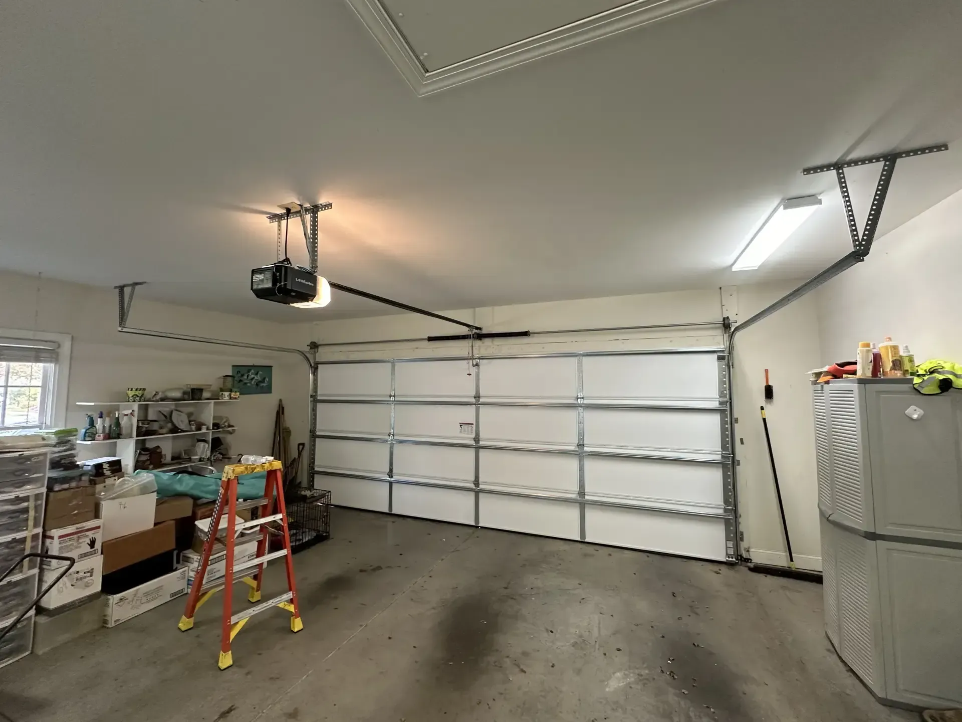 A garage with a garage door open and a ladder.