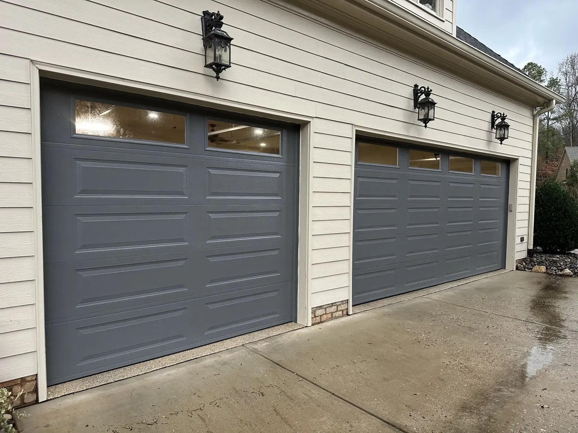 There are three garage doors on the side of a house.