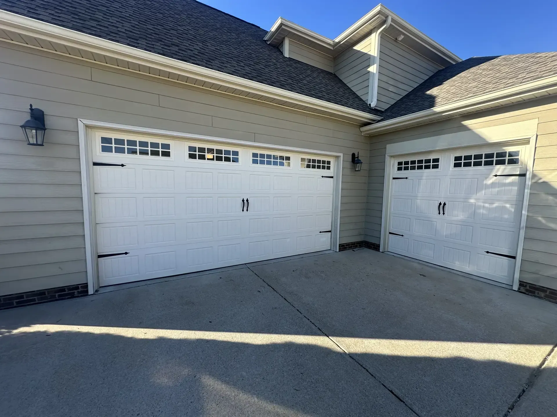 There are two garage doors on the side of a house.