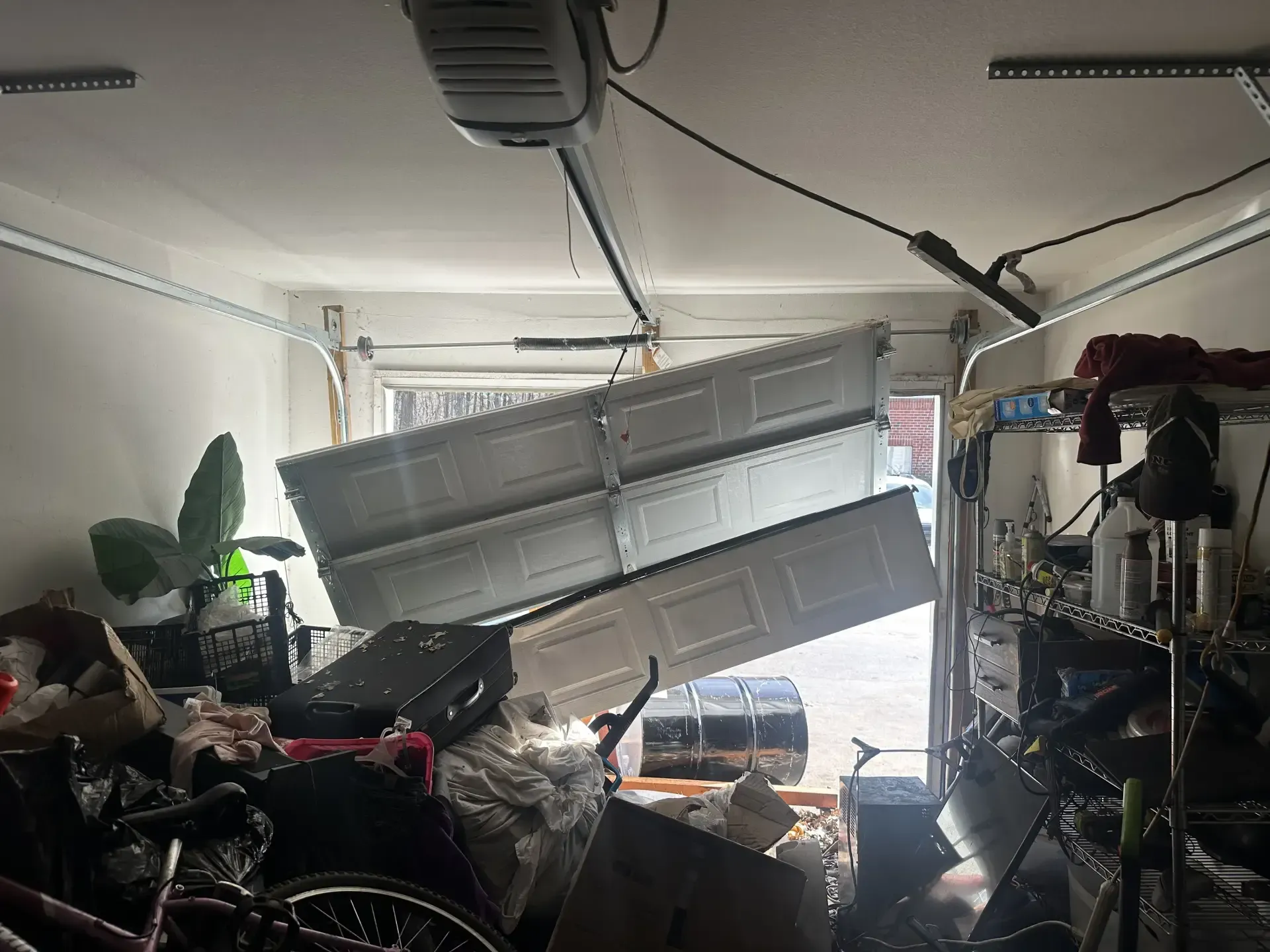 A garage with a broken garage door and a lot of stuff in it.