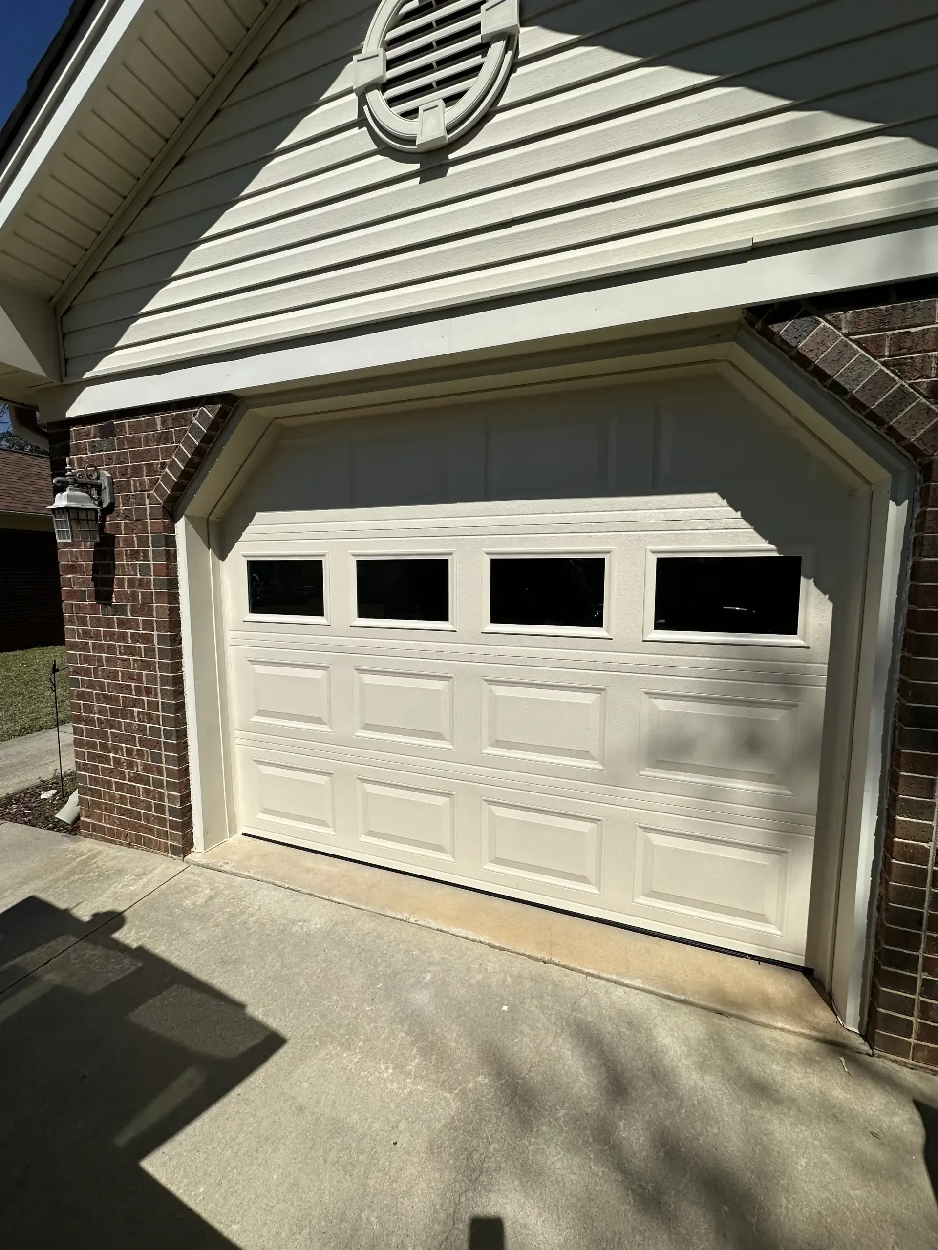 A white garage door is open on a brick house.