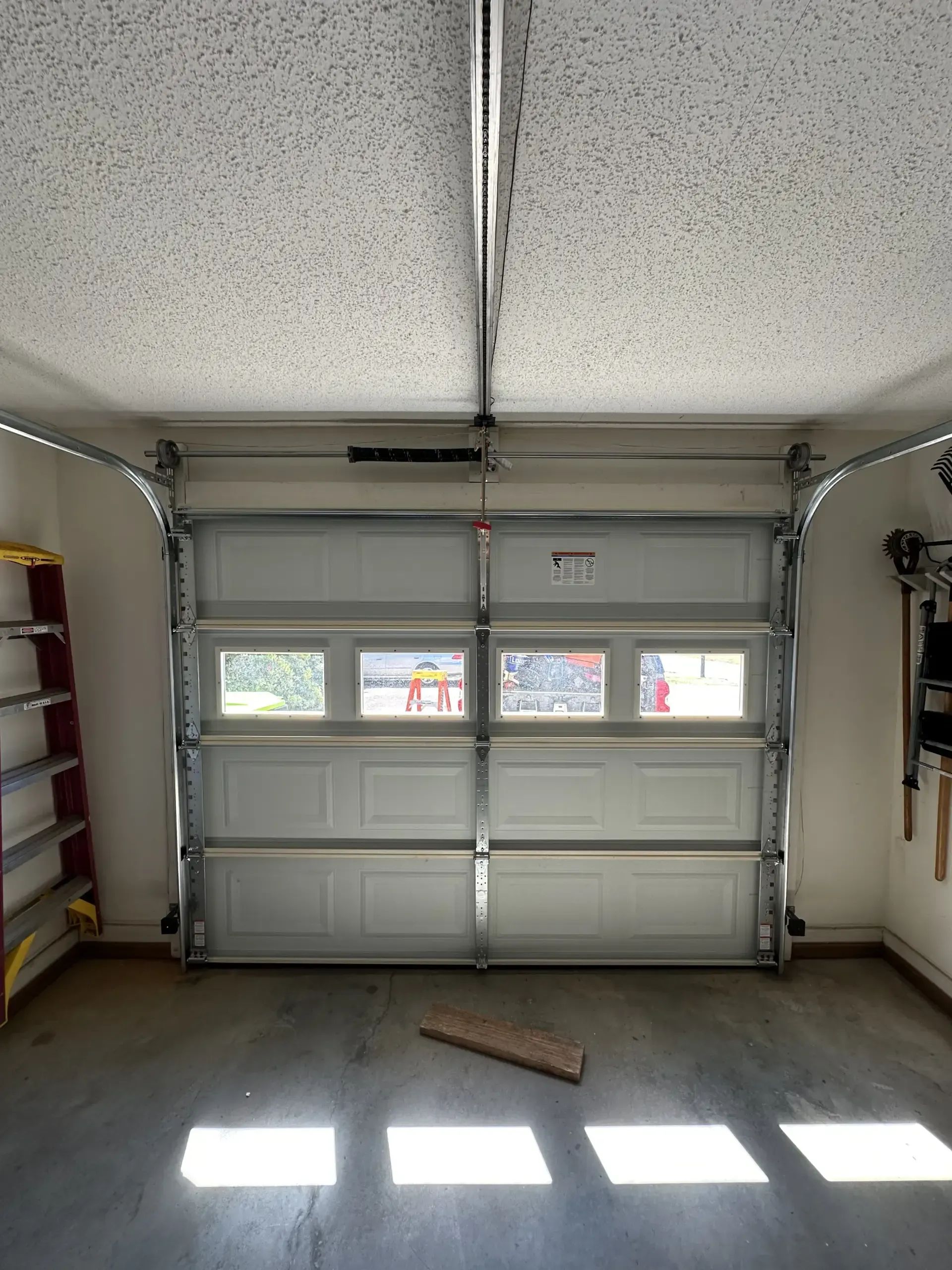 A garage with a garage door open and a ladder.